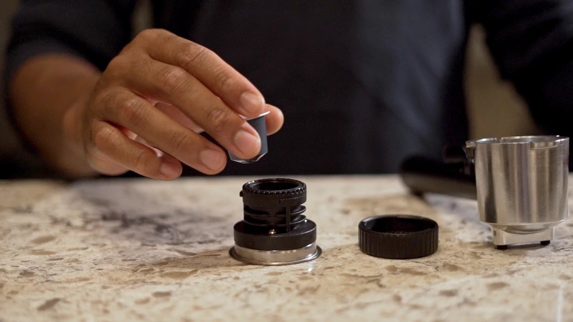 Hands placing an E.S.E pod in the portafilter basket on the countertop