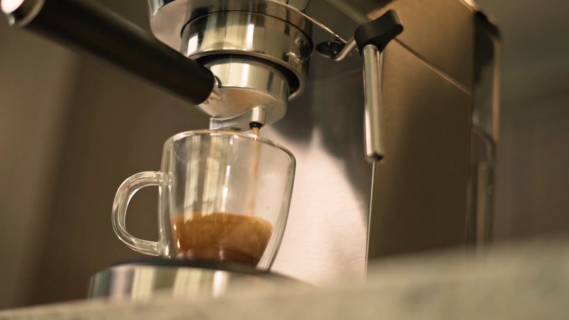 Espresso machine dispensing into a glass mug under the group head spout