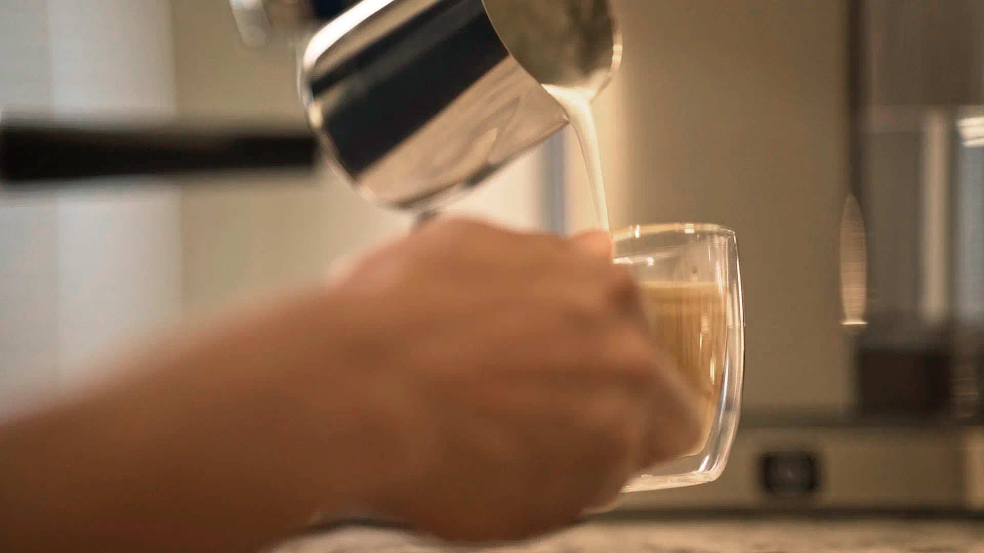 Glass mug under the espresso spout while the machine brews