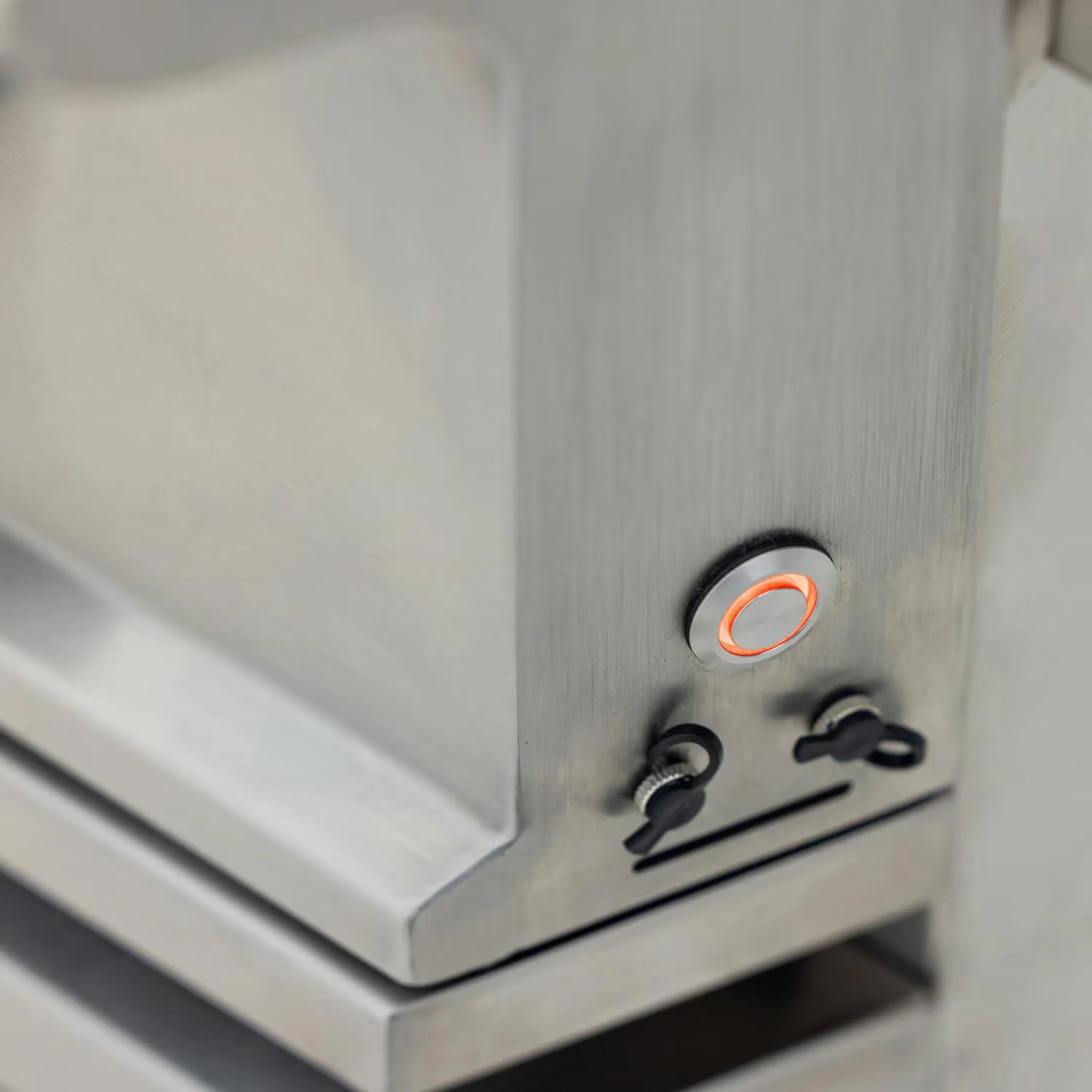 Stainless steel side control panel with orange illuminated button and rotary knob