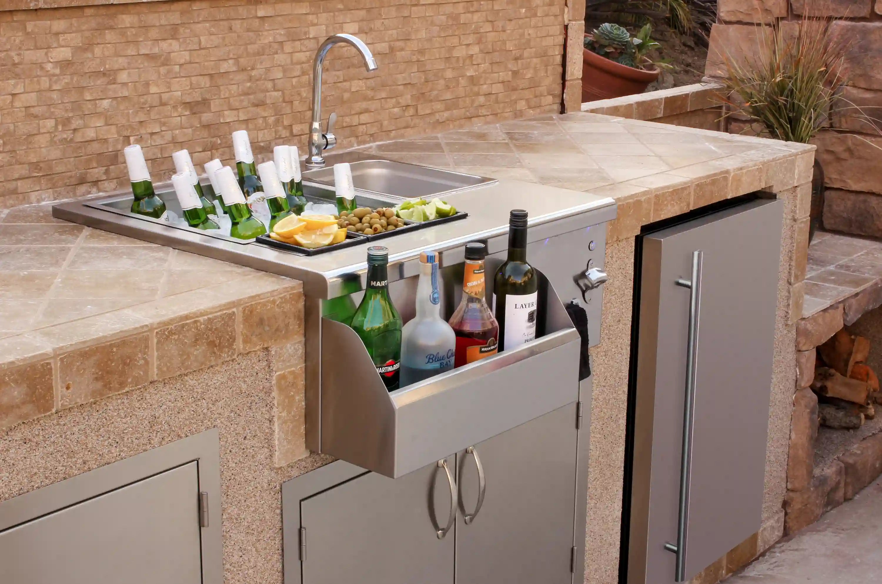 Outdoor stainless beverage center with bottle storage drawers, faucet, and counter
