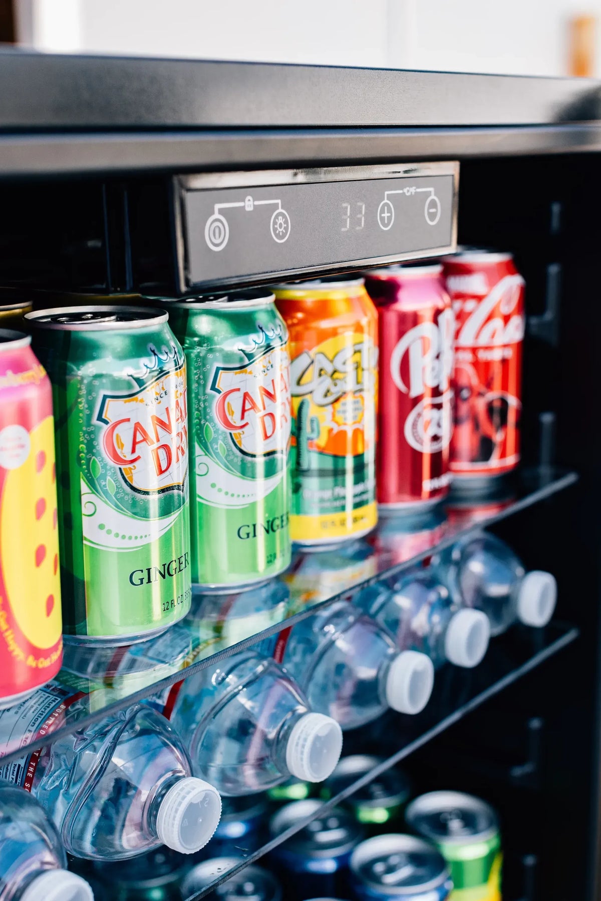 Outdoor beverage fridge interior with cans and a row of clear bottle holders