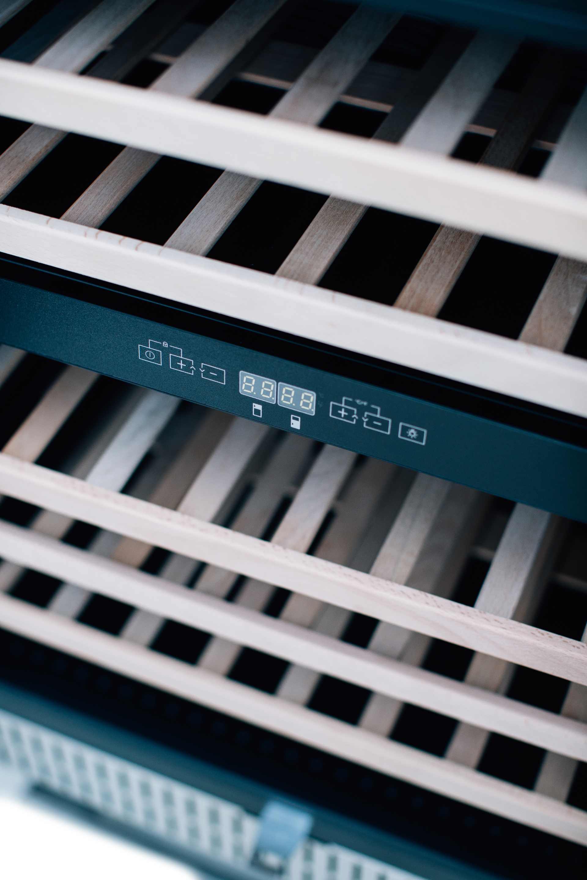 Wine cooler interior control area with display and evenly spaced bottle racks