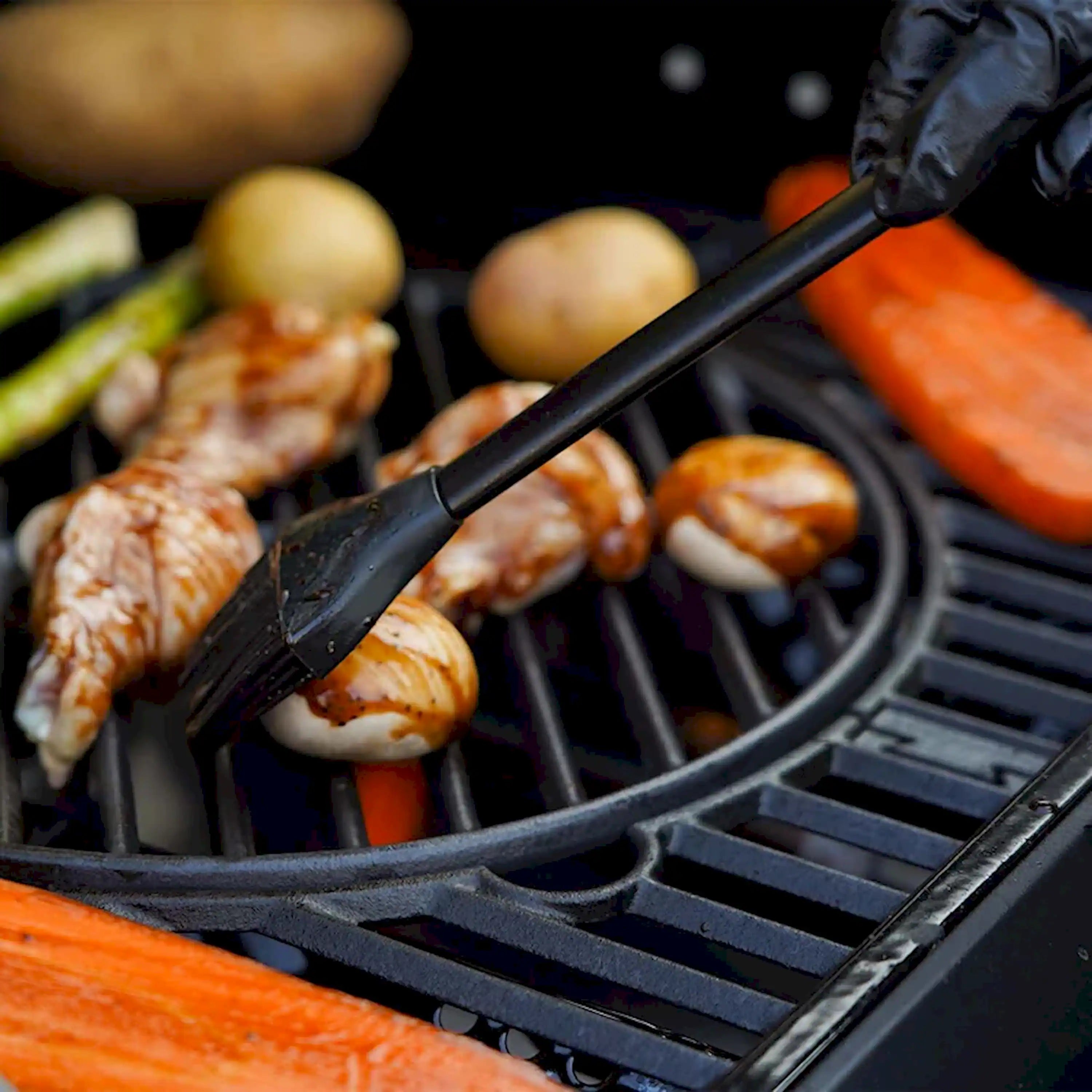 Black cast iron grill grate with tongs lifting browned chicken and onions
