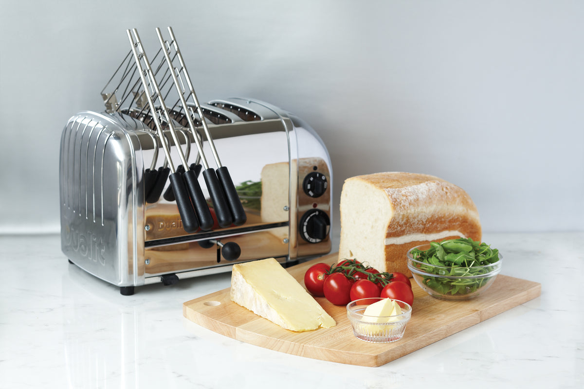 Chrome sandwich toaster with warming rack, black handles, and toast with toppings on board
