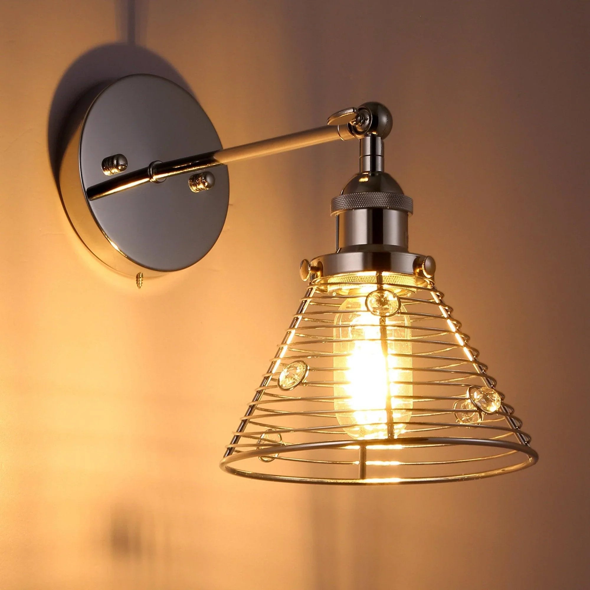 Silver wall sconce with wire cage shade and round backplate, lit bulb visible