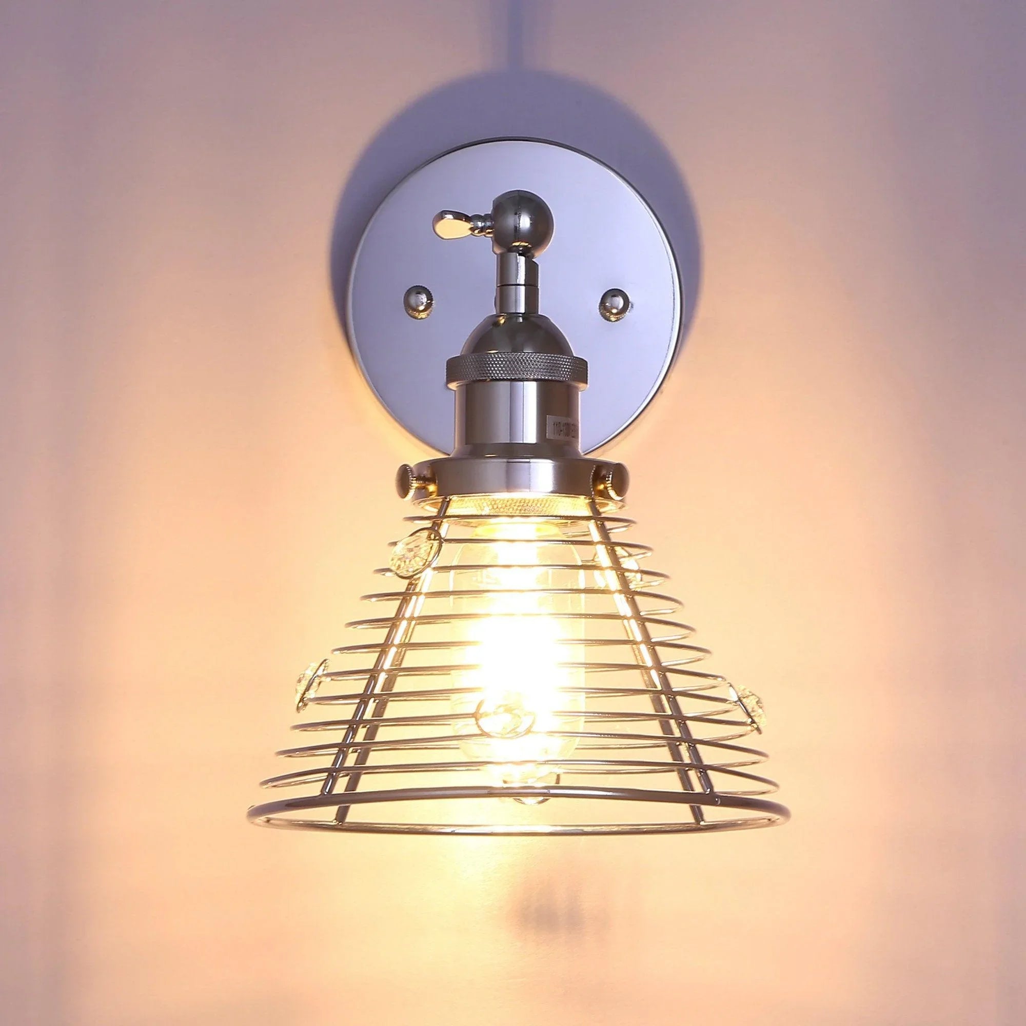 Silver wire cage wall sconce glowing through the metal shade