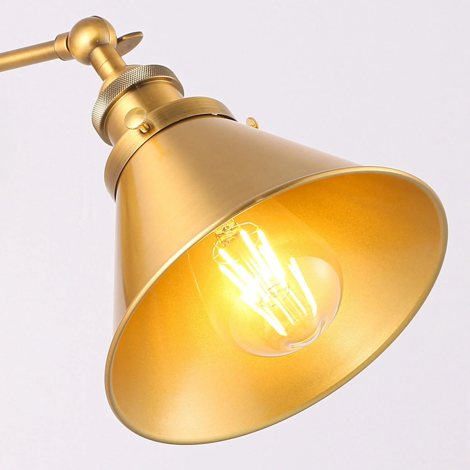 Golden brass bell shade with visible glowing filament bulb and metal socket details