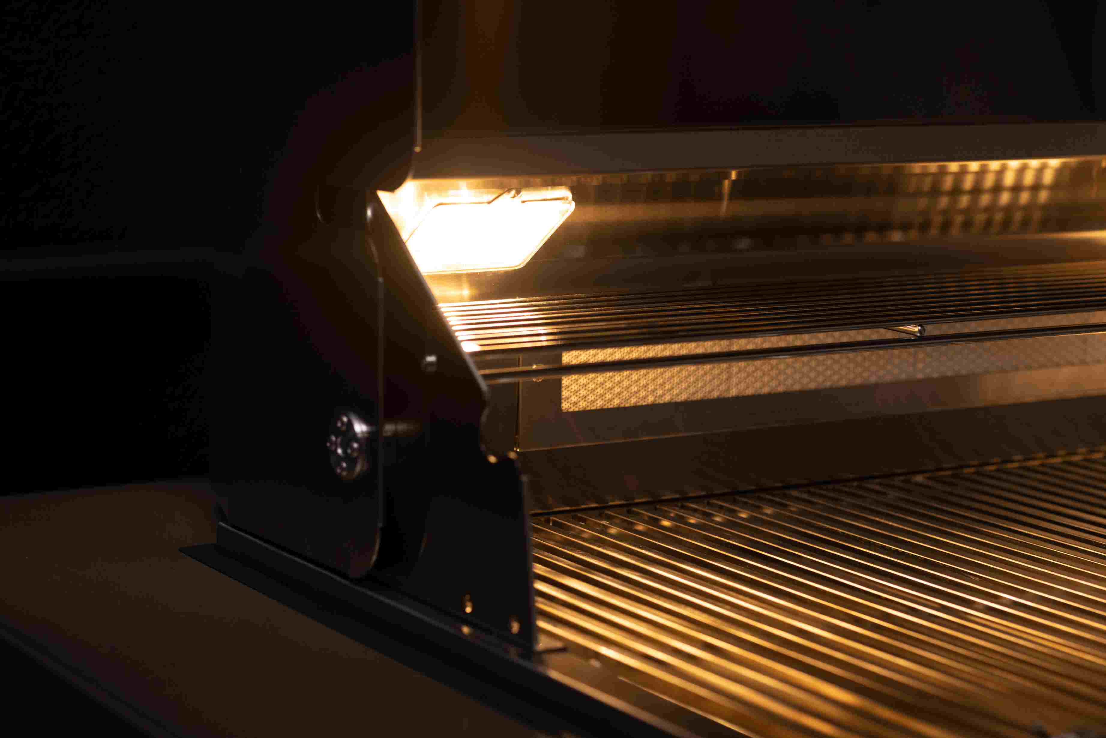 Stainless steel gas grill with lid open showing glowing burners and grates