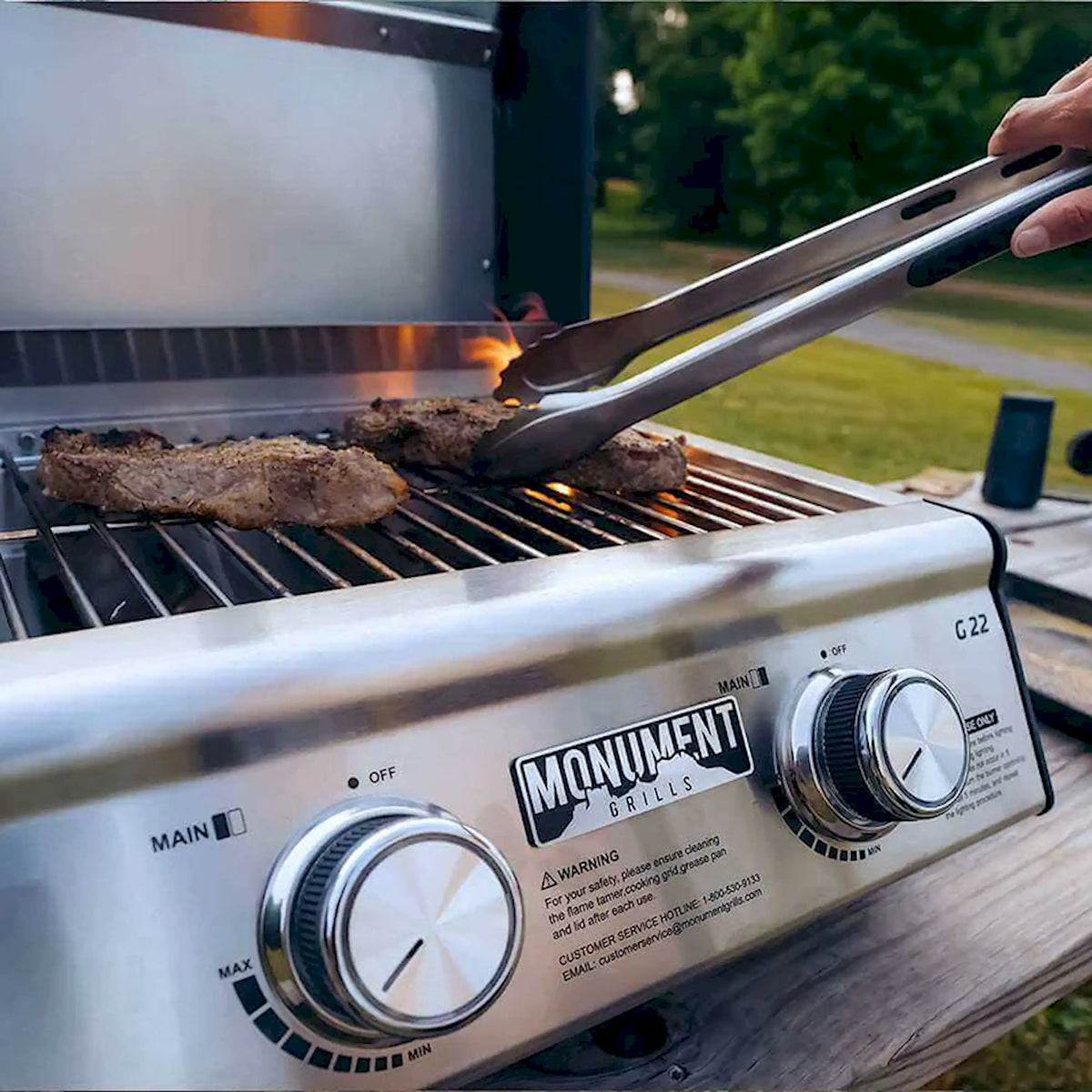 Propane grill front controls with spatula lifting a browned burger