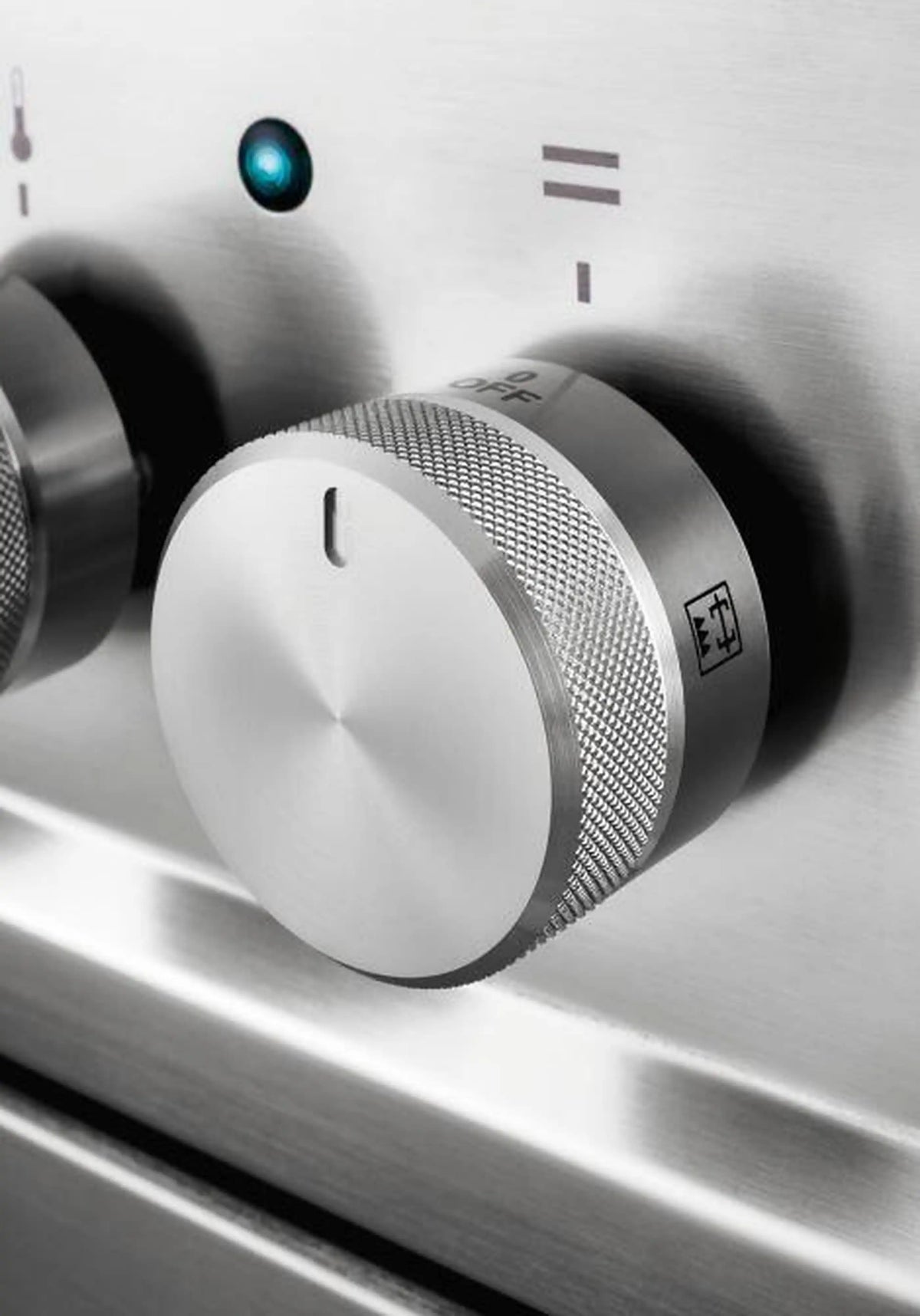 Induction control knob and textured dial on glossy black cooktop surface