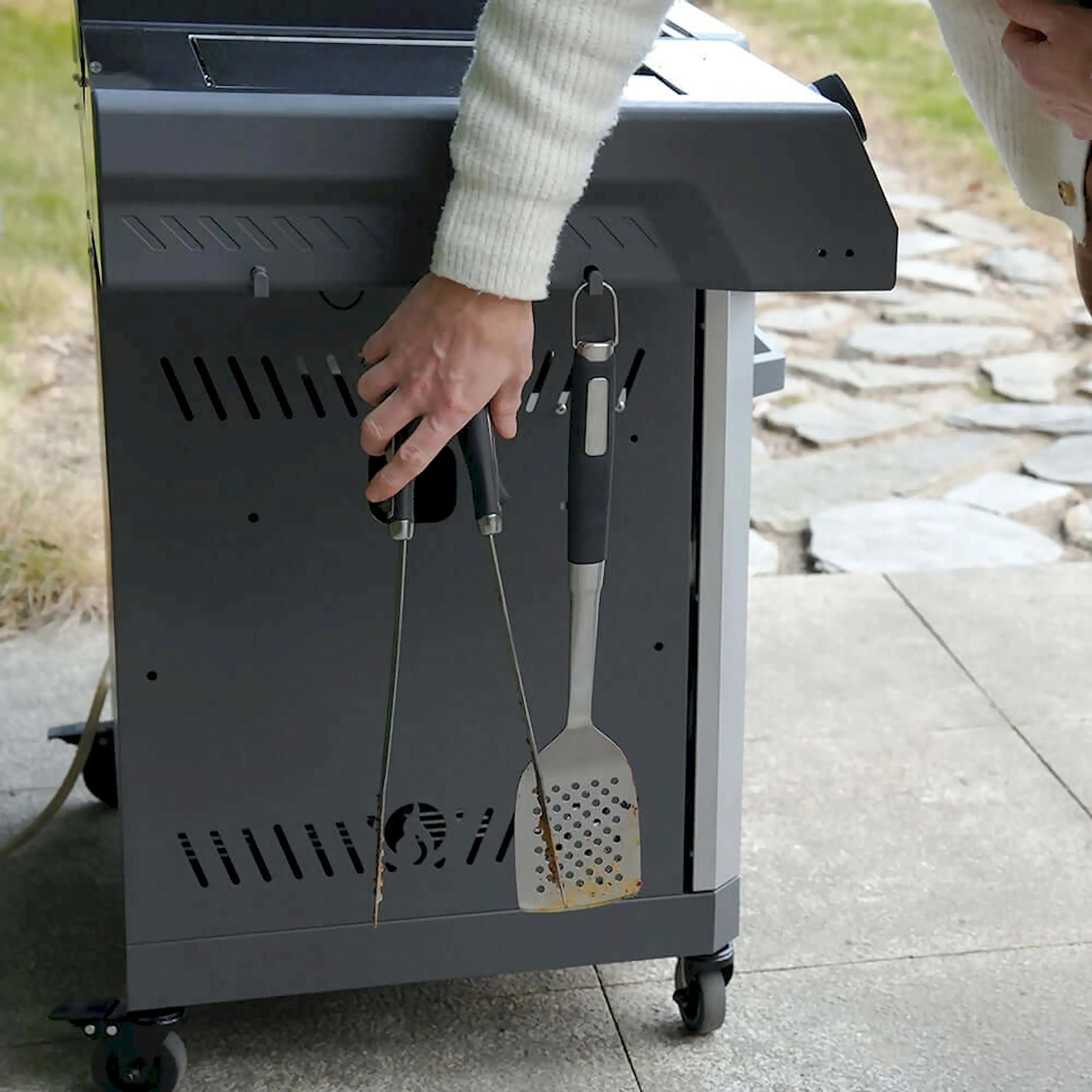 Propane gas grill with hanging spatula and grill tools on front panel