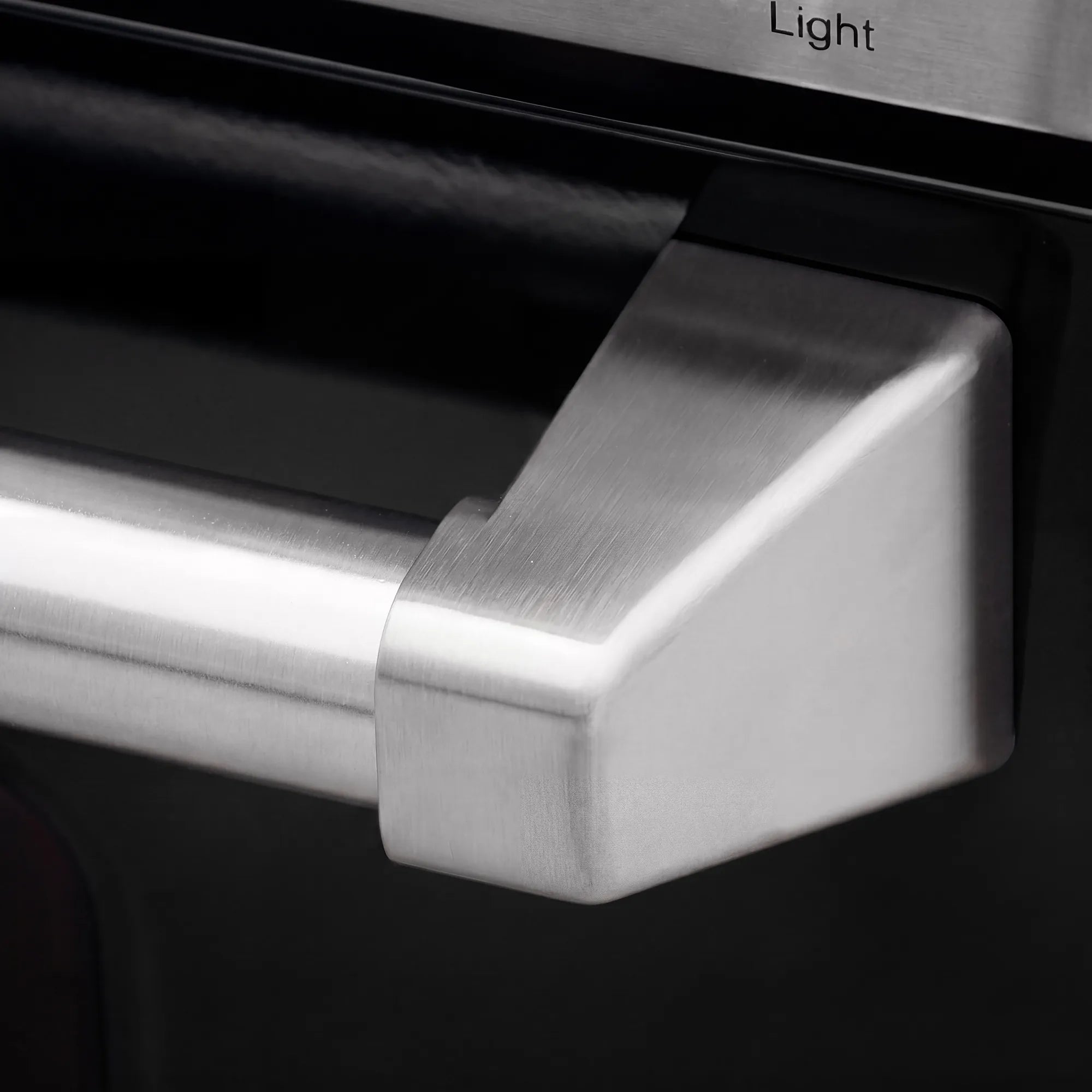 Stainless oven door handle and control trim on a black electric range