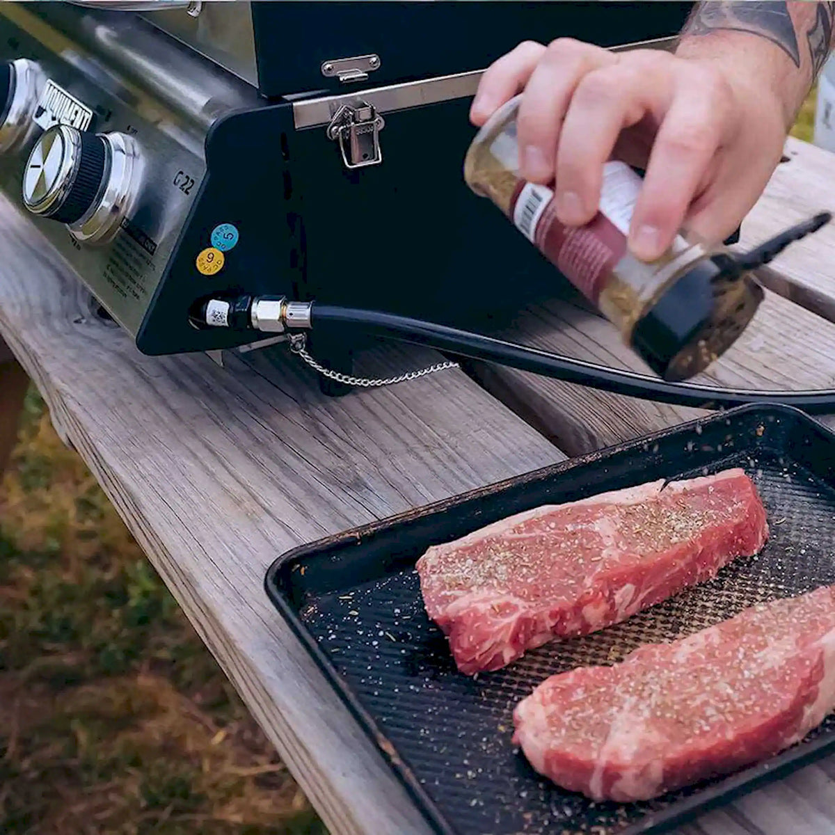 Tabletop propane grill with steaks cooking on the grates