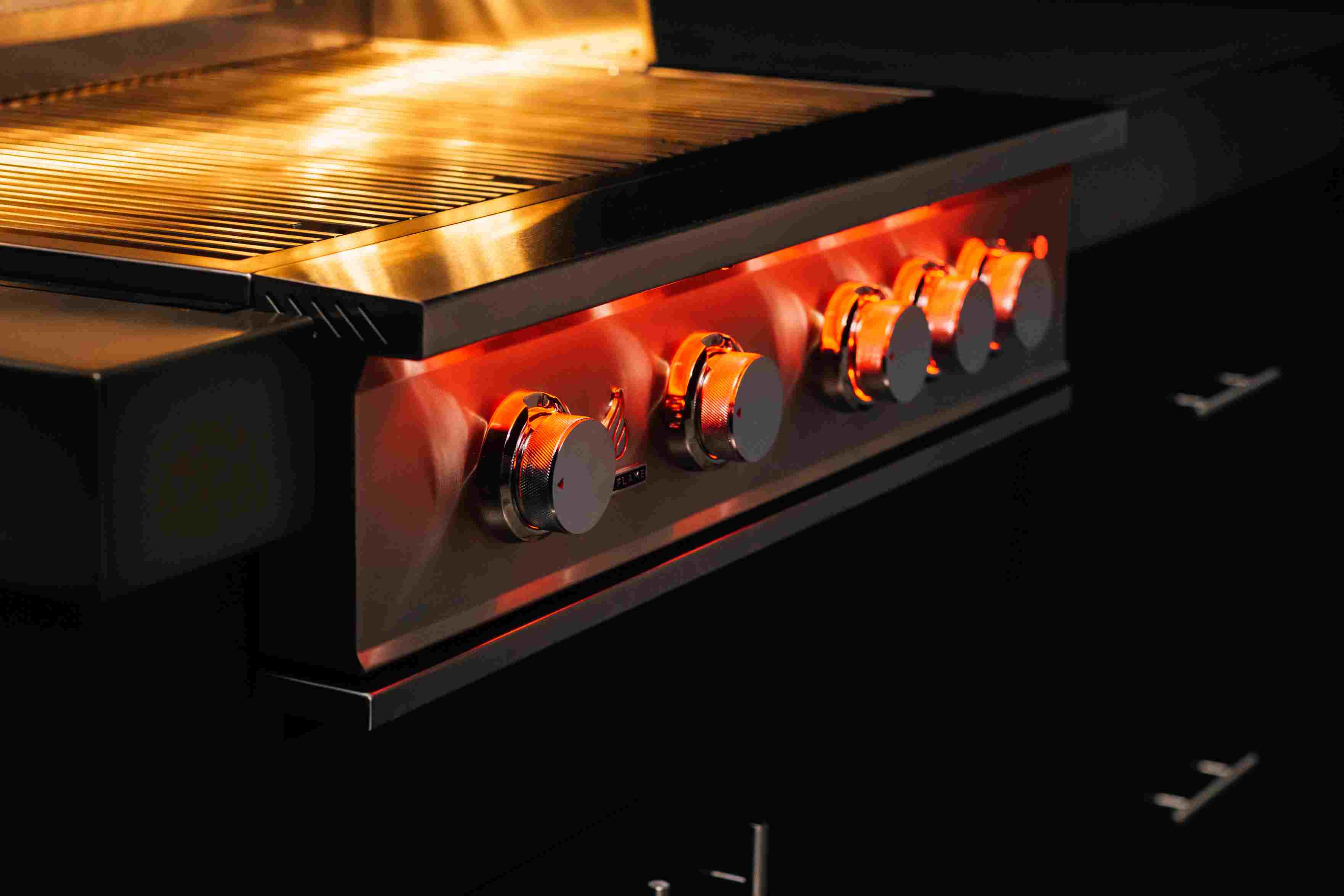 Stainless steel natural gas grill with glowing burners and control knobs