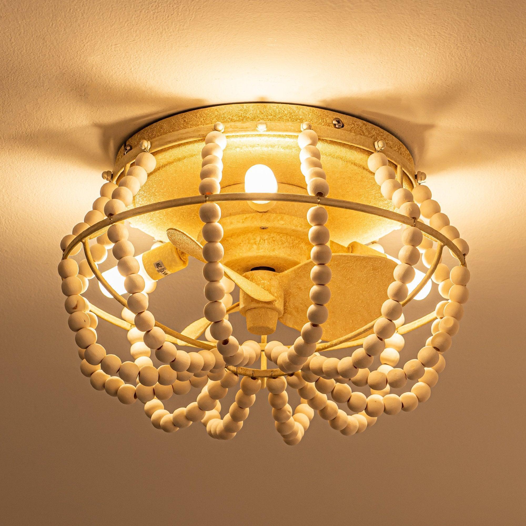 Beige flush-mount ceiling fan light illuminated with beaded fringe and blade accents