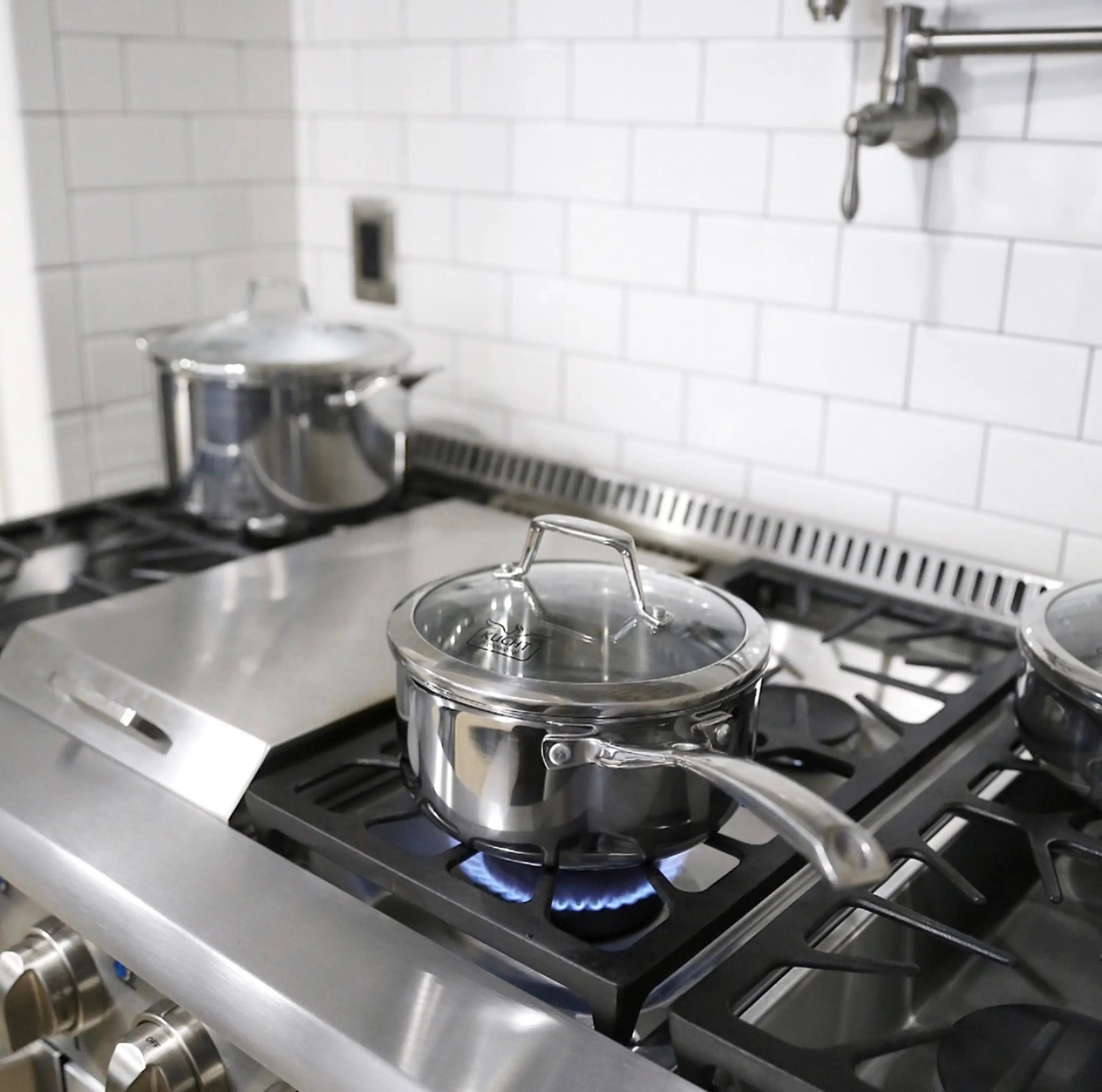 Stainless steel stockpot with lid on gas cooktop