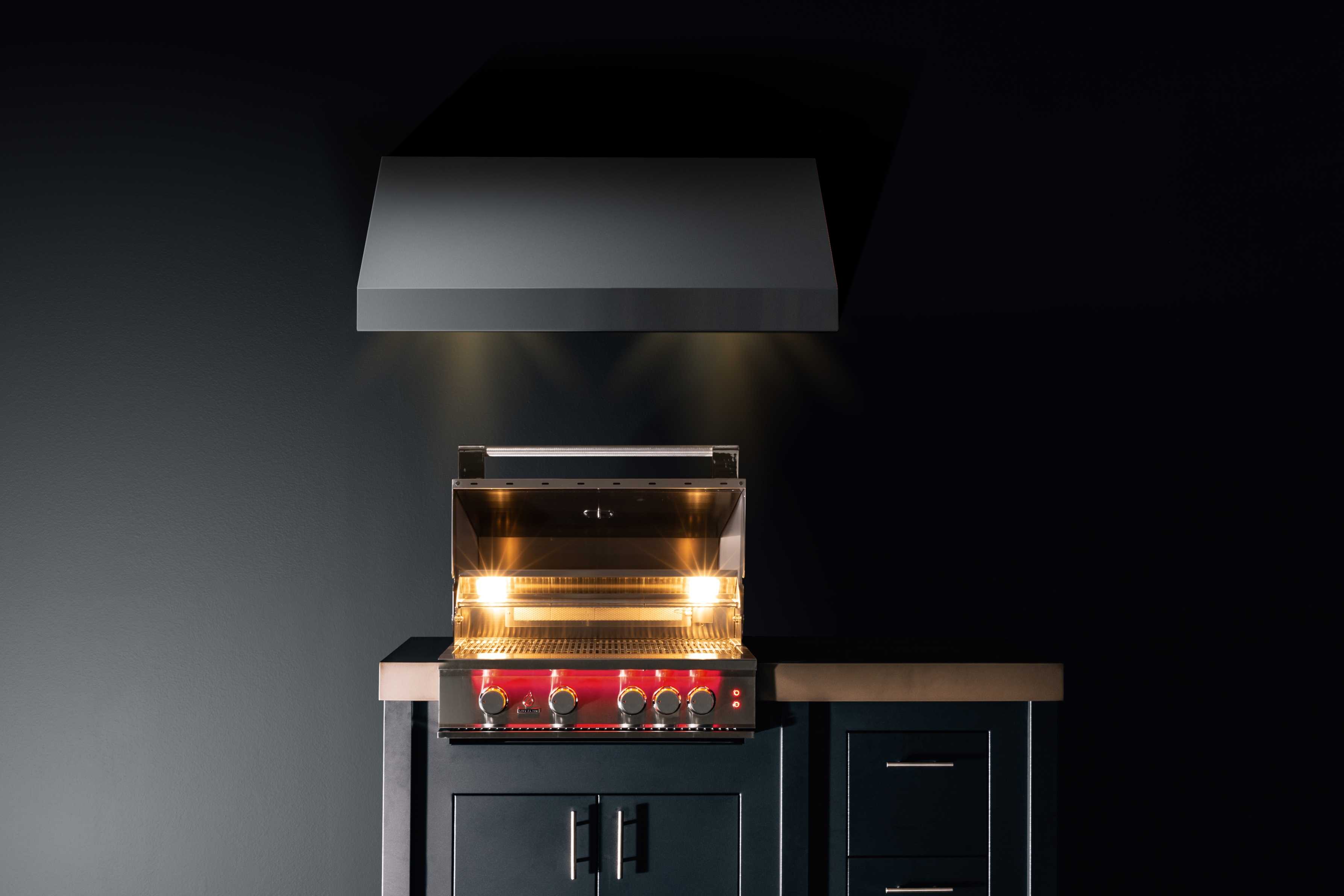 Stainless built-in propane gas grill with lit burners and side control knobs
