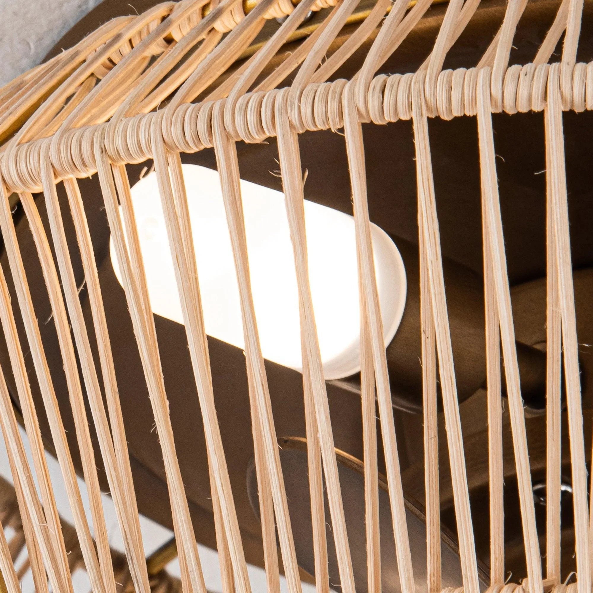 Close-up of golden rattan-style fan cage with visible LED bulb holders