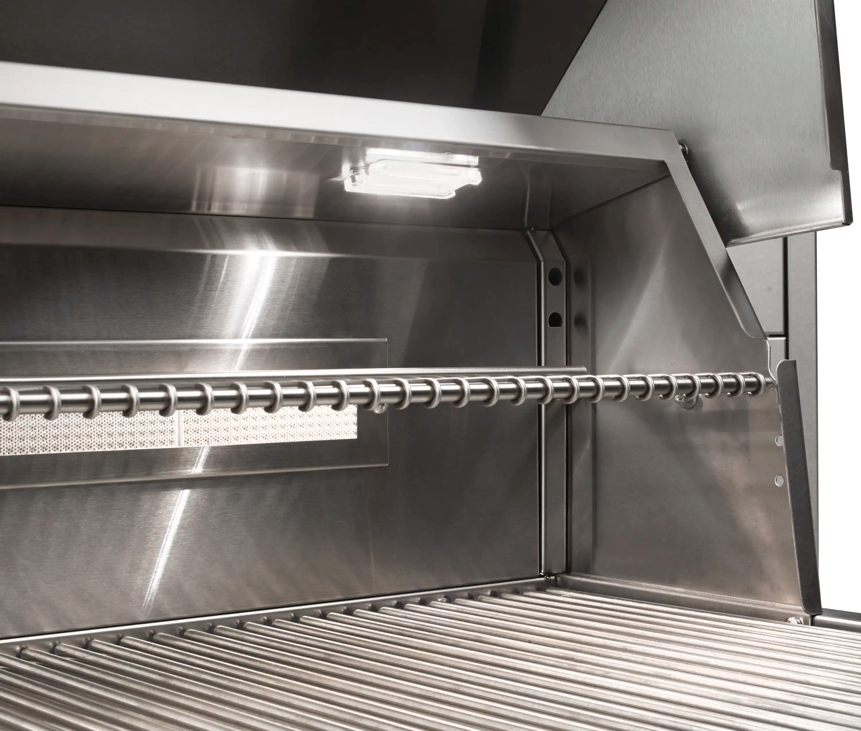 Stainless gas grill interior with rotisserie rod and overhead light