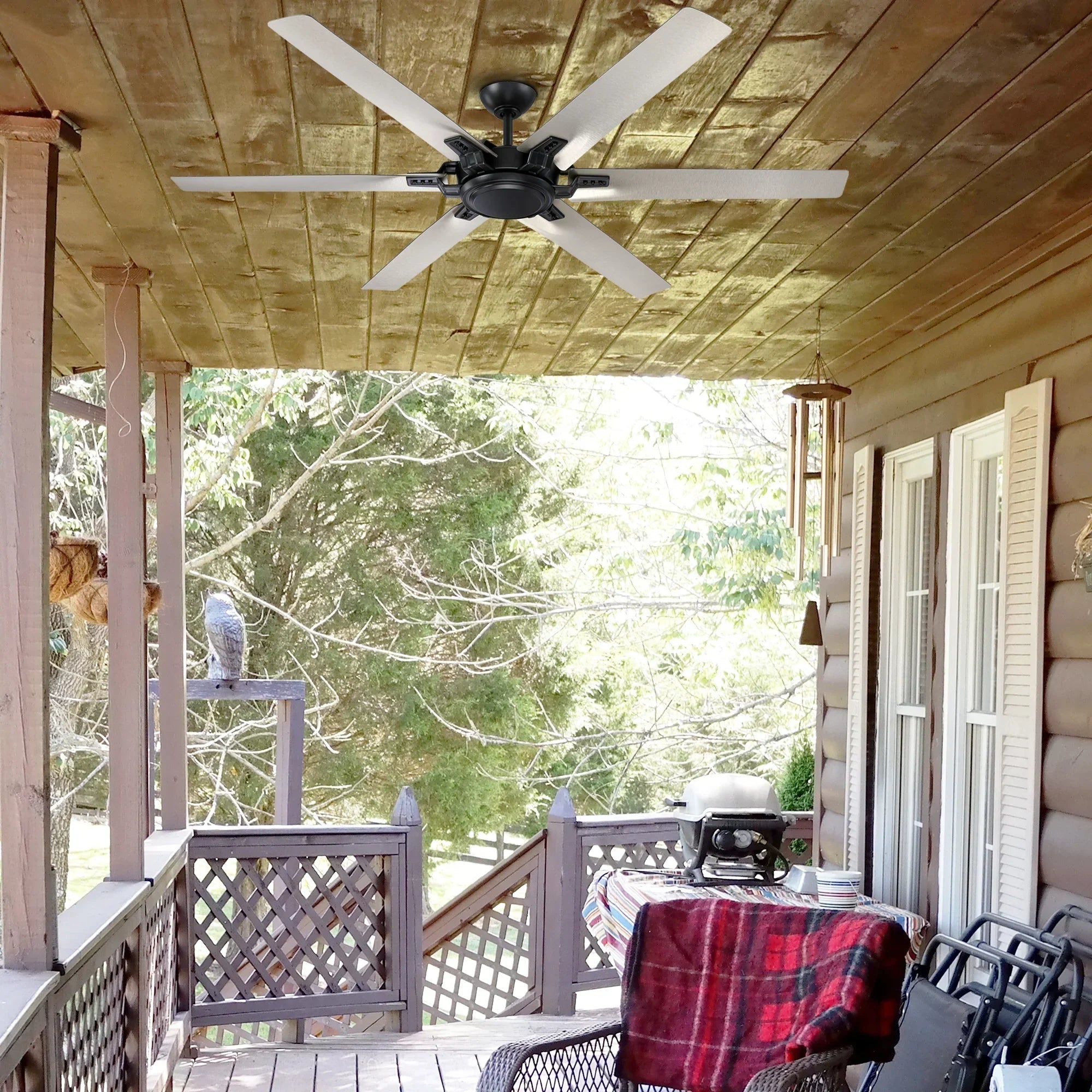 Black industrial ceiling fan with 5 blades under wooden porch ceiling.