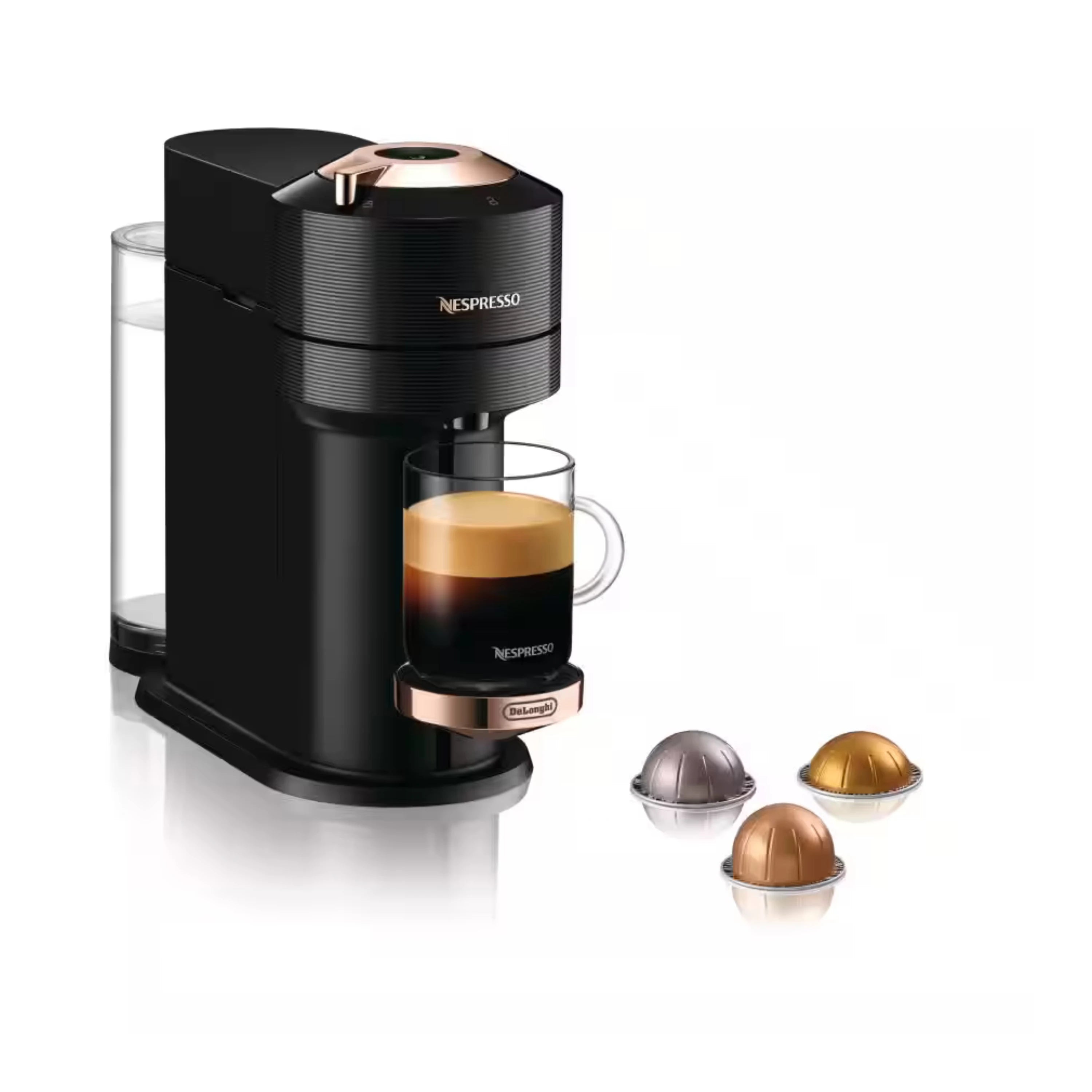 Black coffee maker with rose-gold top, glass mug, and three capsule pods on stand