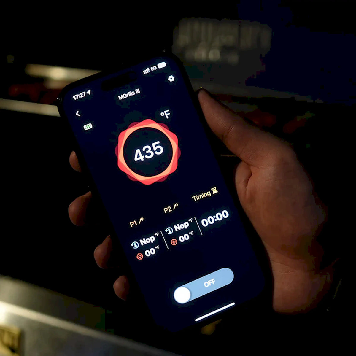 Hand holding phone showing Monument grill app with temperature set at 436°F