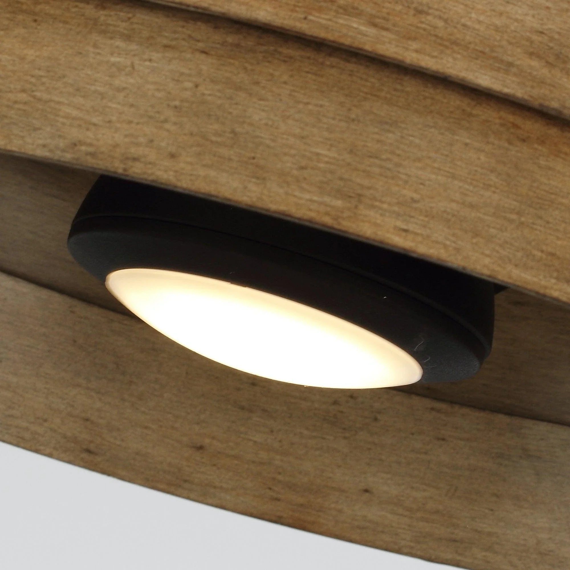 Close-up of underside of brown flush mount LED ceiling fan with glowing integrated light