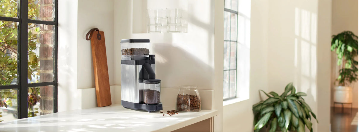 Polished silver burr grinder on countertop with black catch container