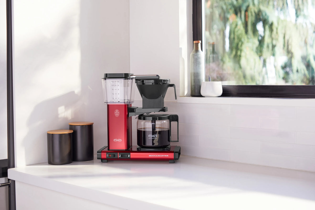 Candy apple red coffee maker on counter with glass carafe and black base controls