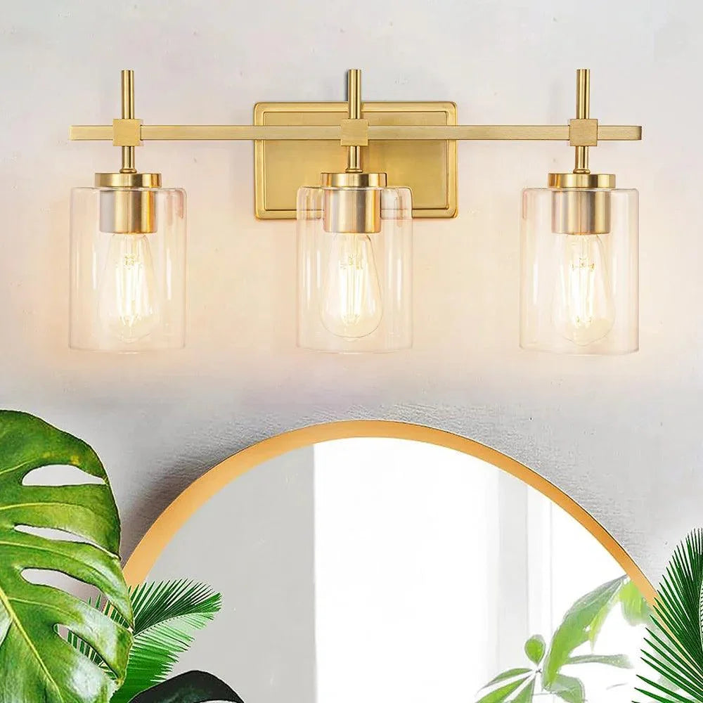 3-light bathroom vanity light lit, golden frame with clear glass shades and gold accents