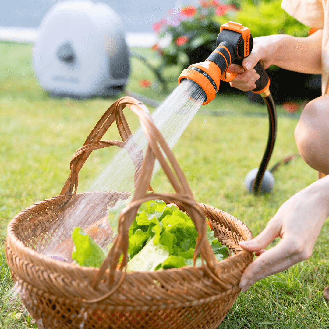 Orange garden hose nozzle spraying water from a connected retractable hose reel