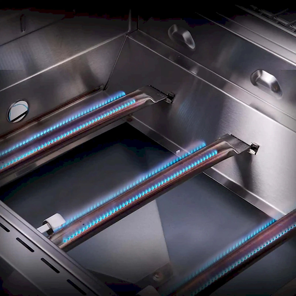 Infrared burner tubes glowing inside the stainless grill firebox