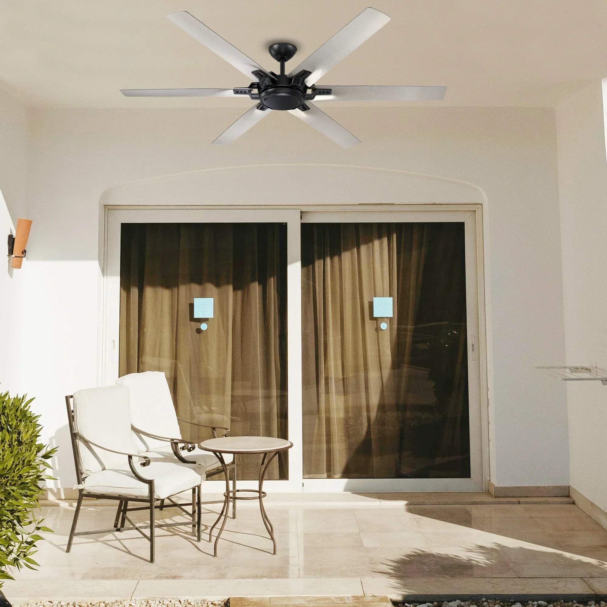 Black industrial ceiling fan with 5 blades mounted on ceiling above patio door.