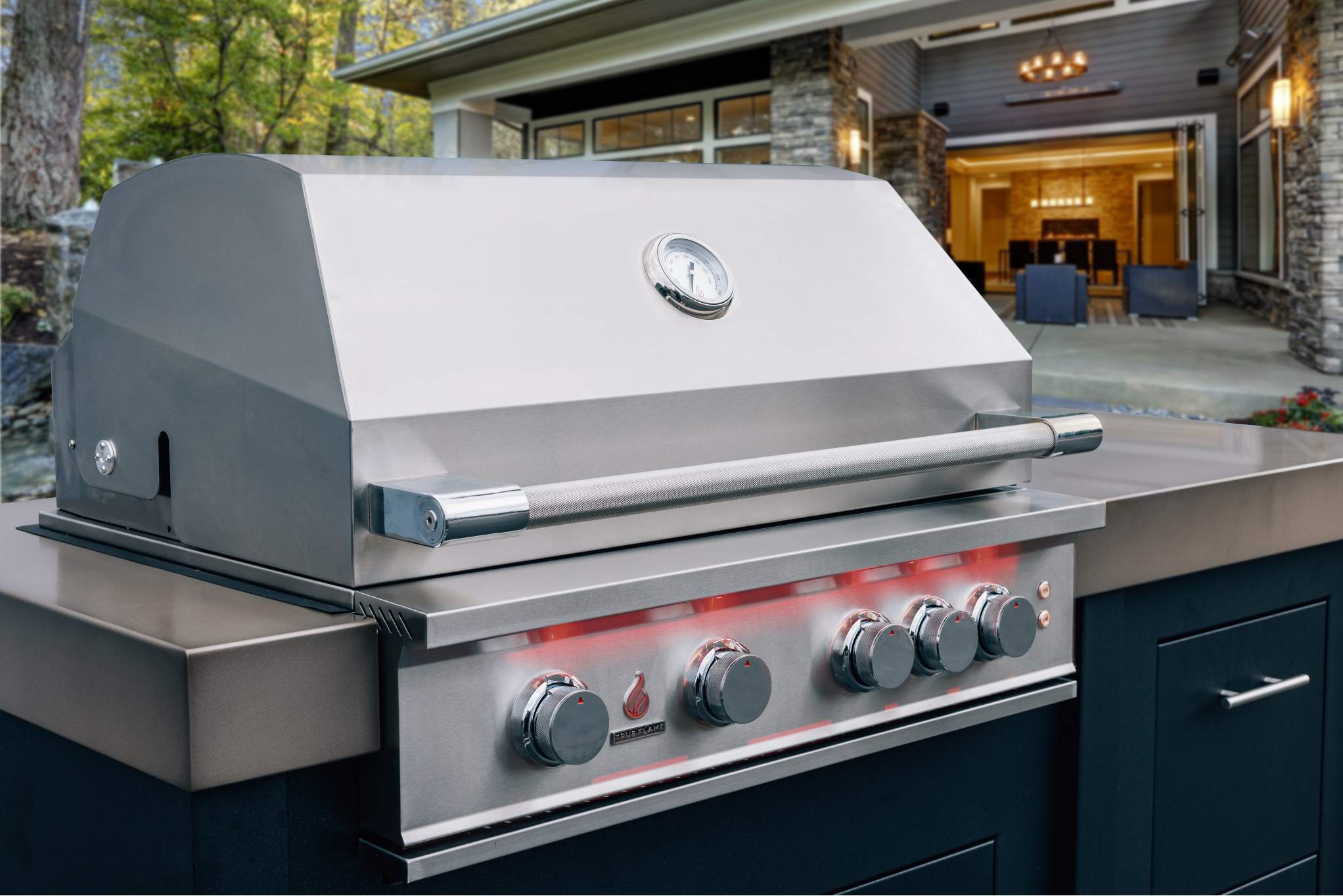 Stainless steel propane gas grill with open lid on built-in outdoor kitchen island