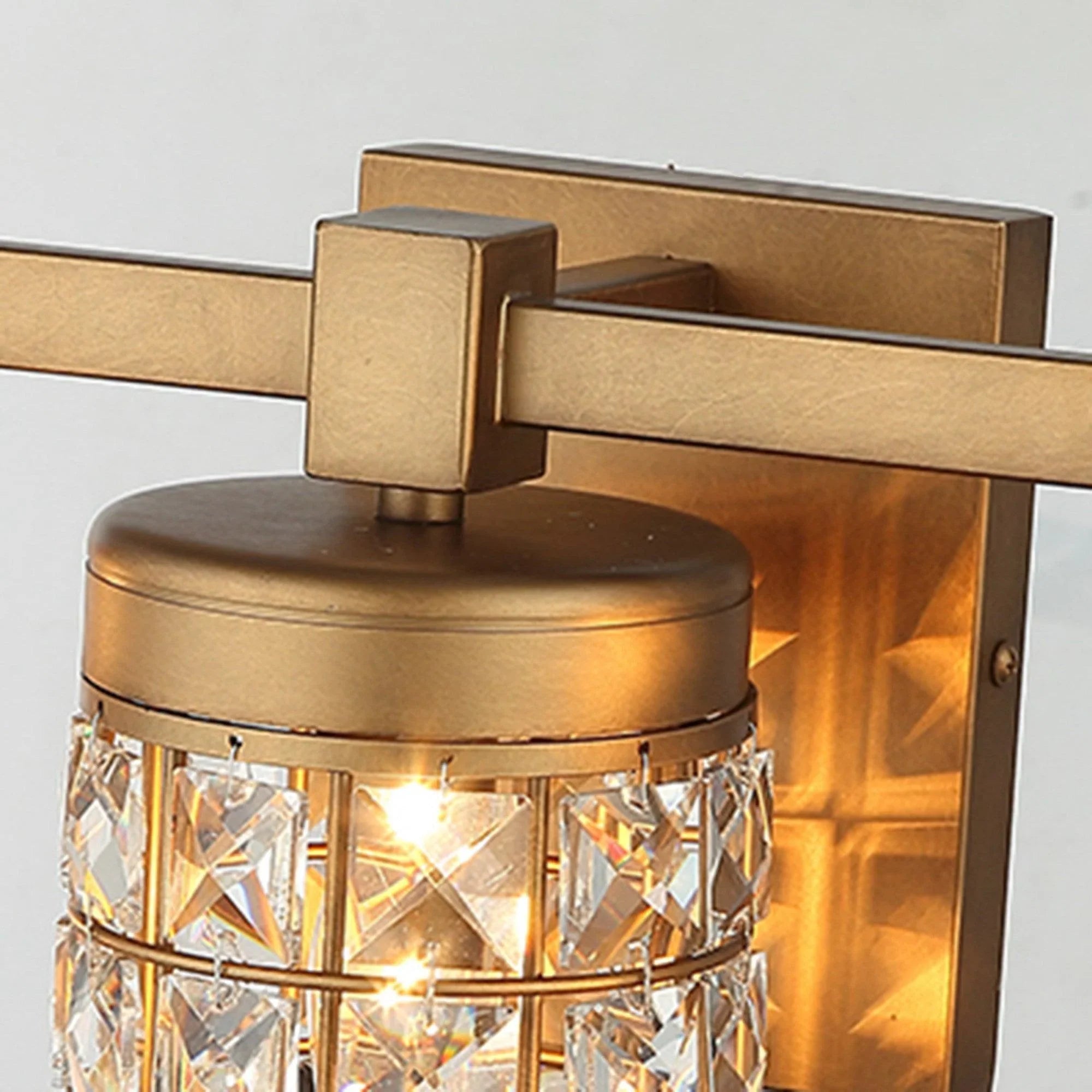 Golden vanity wall light with round cap and faceted crystal glass cylinder, close-up