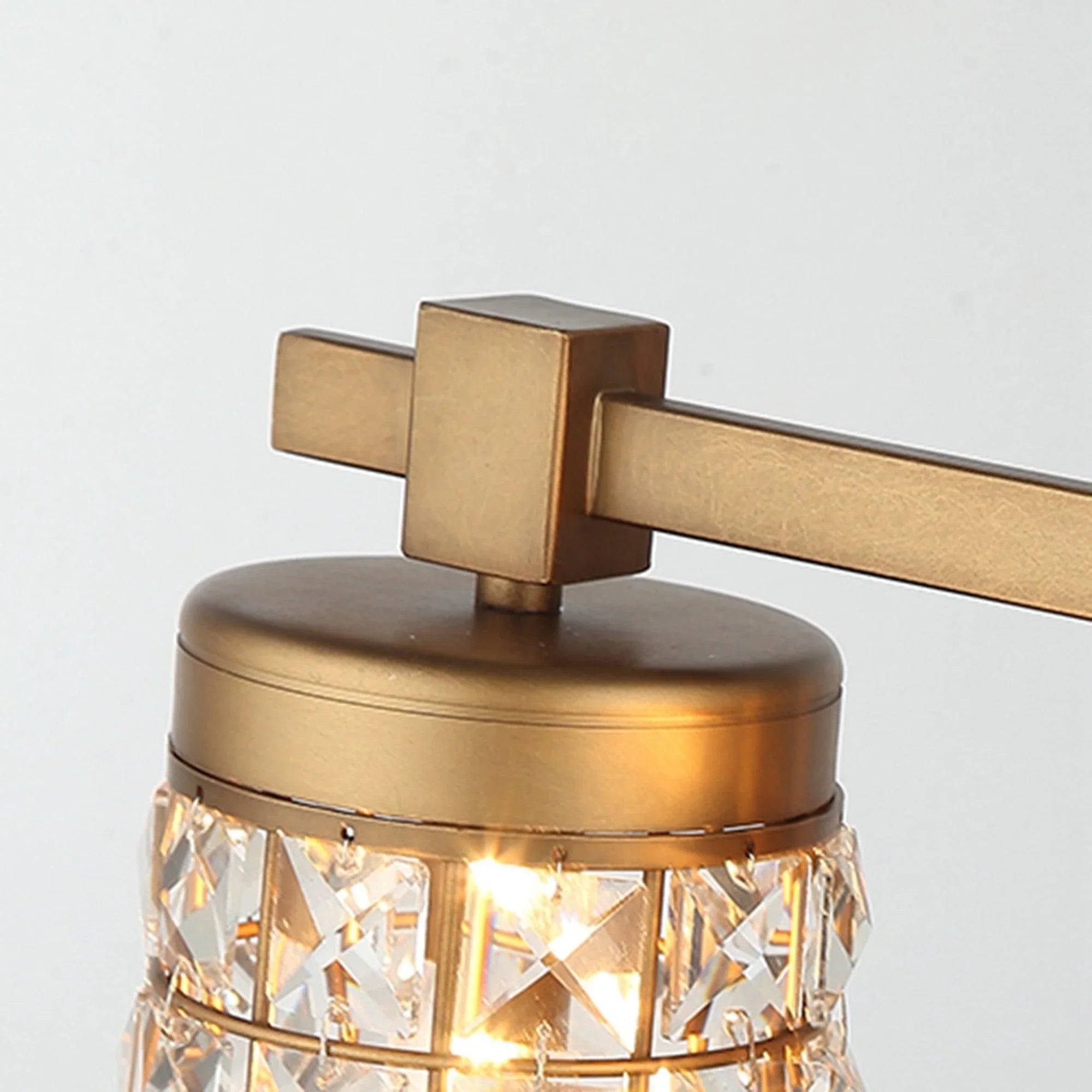 Golden vanity light shade top with metal hub, square brackets, and glowing faceted crystal
