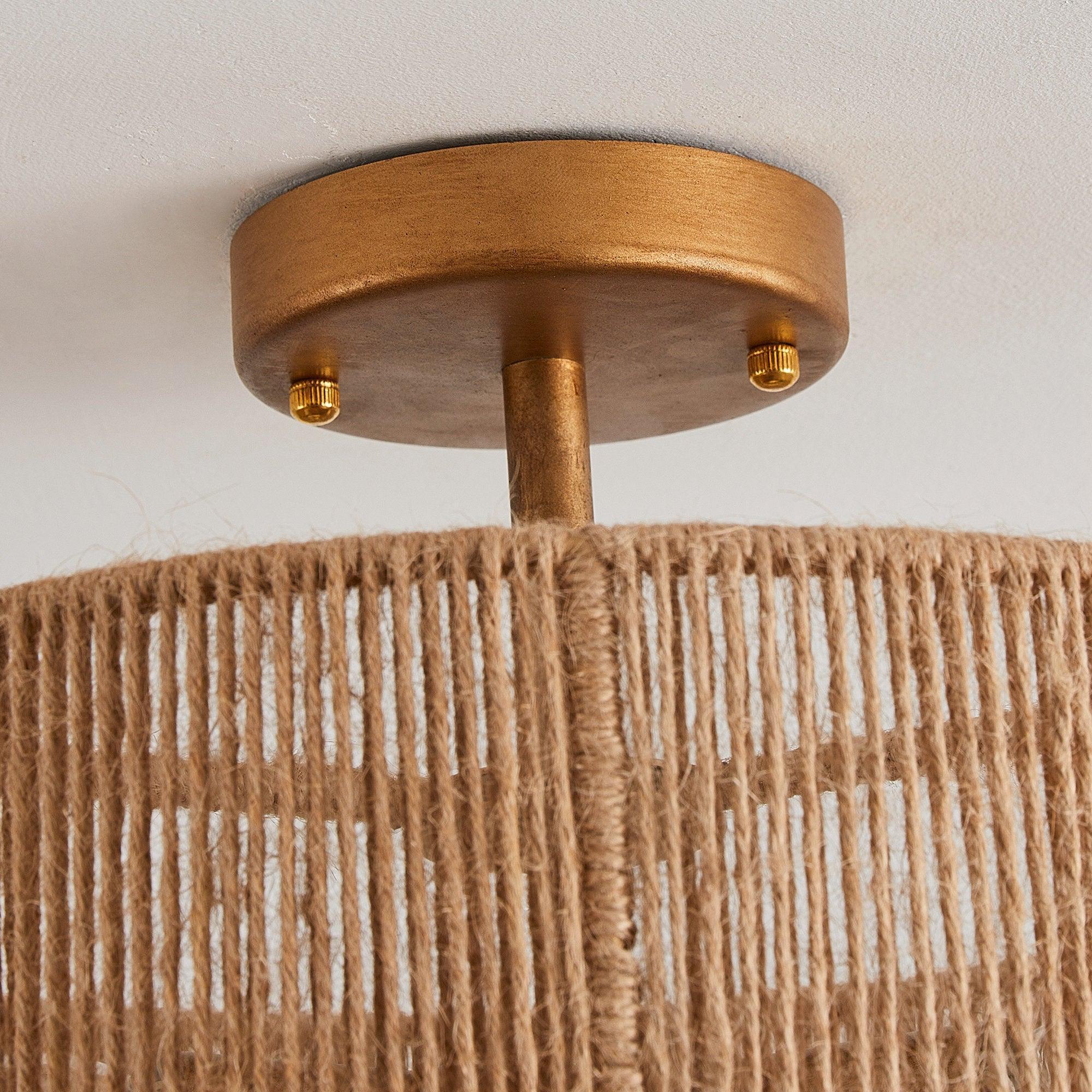 Close-up of golden brass canopy and central downrod above woven shade.