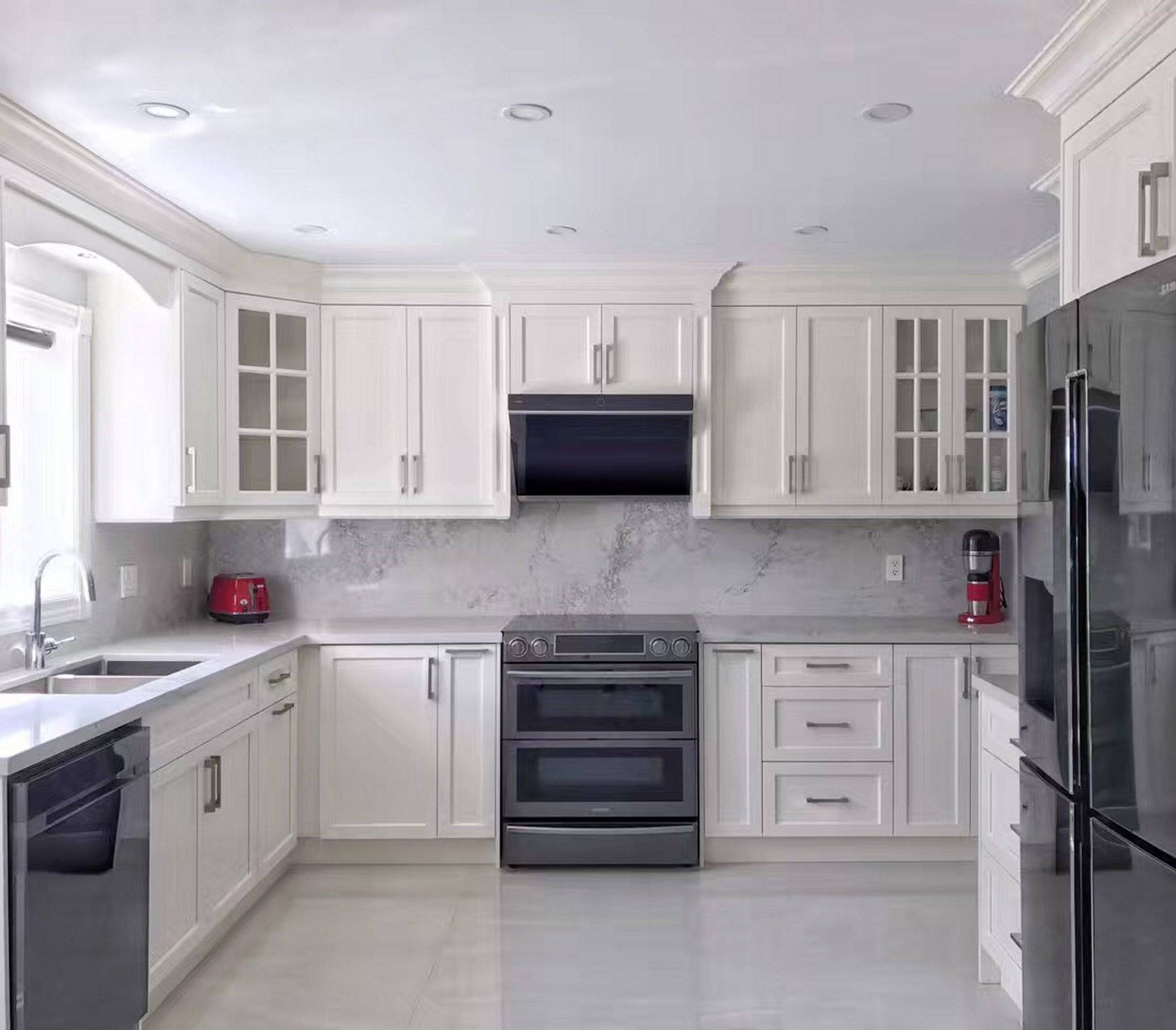 Black and stainless slant range hood installed under kitchen cabinets with vent grille