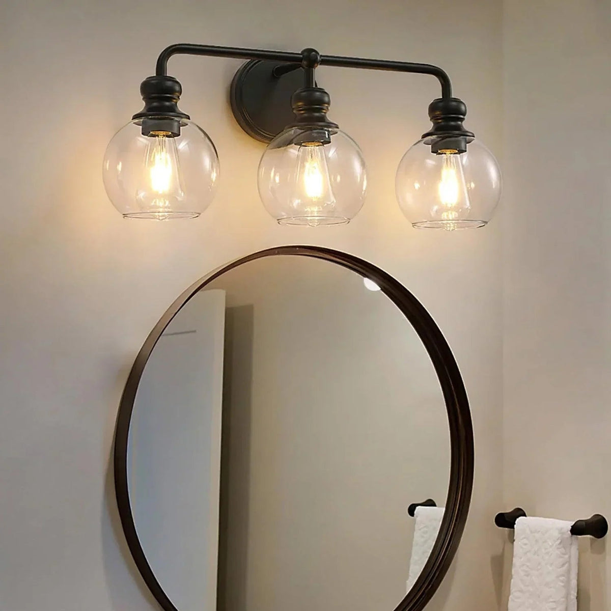 Black 3-light vanity light with clear glass globe shades and wall-mount backplate