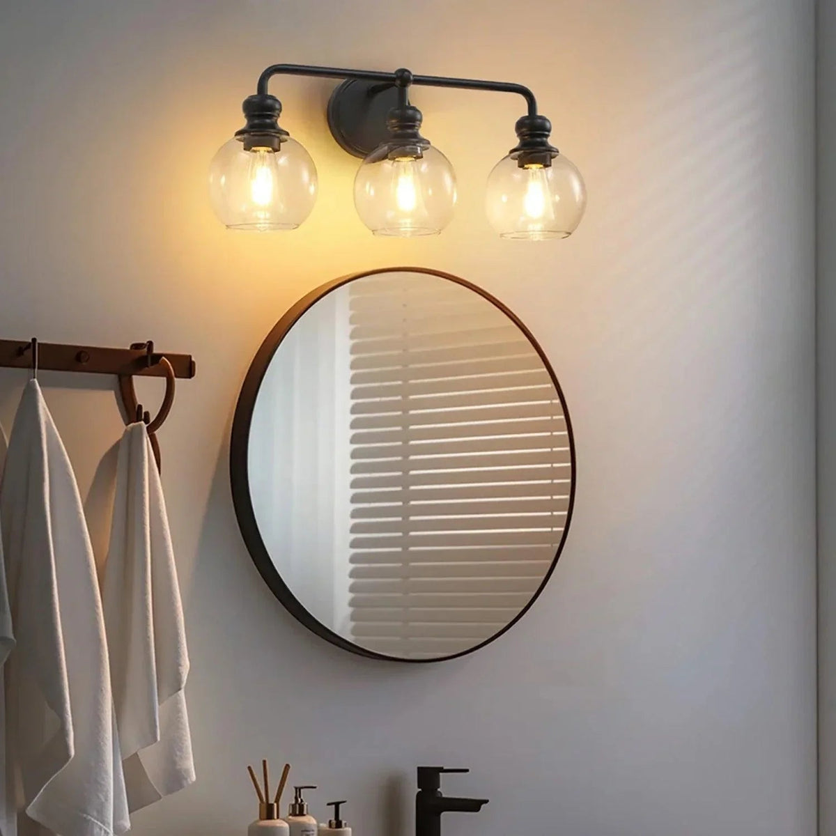 Black 3-light vanity light with three clear glass globe shades and curved metal frame