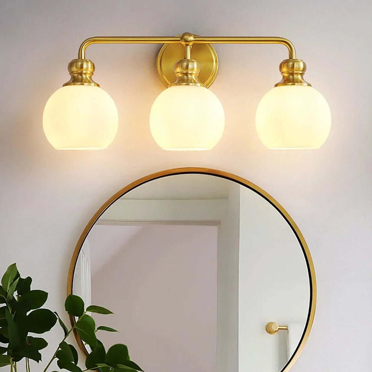 Gold 3-light vanity light with frosted glass dome shades and arched metal bar