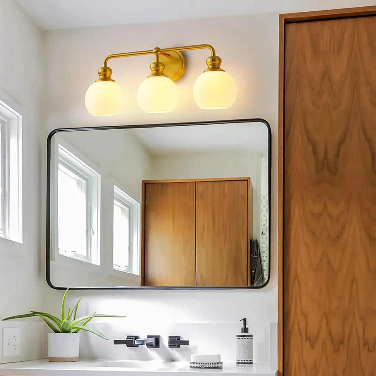 Gold 3-light vanity light with frosted glass dome shades on arched wall mount