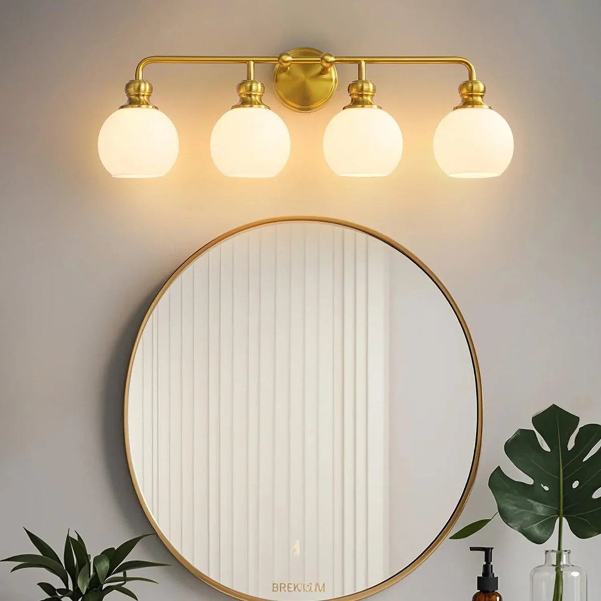Golden 4-light vanity light over round mirror with frosted glass globe shades