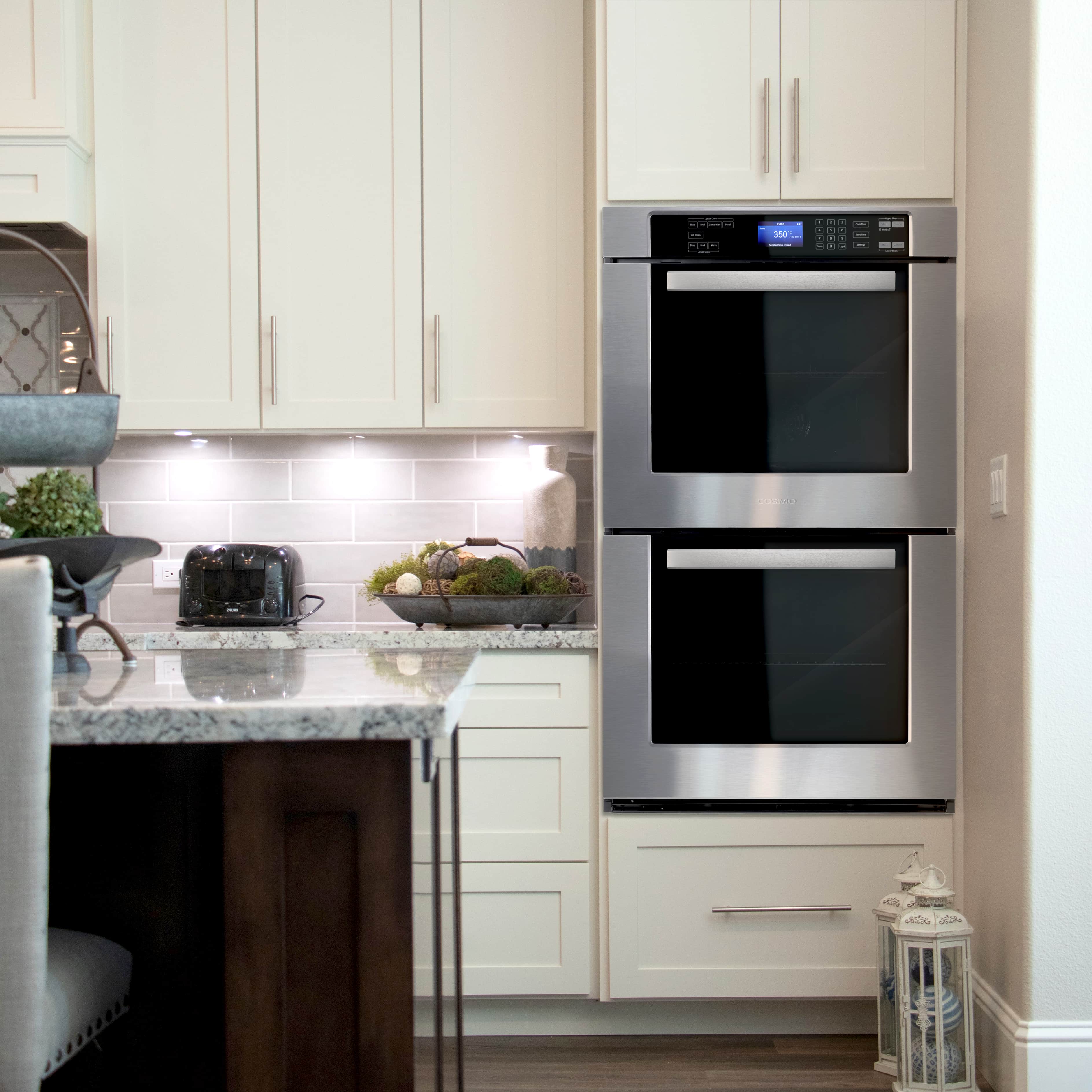 Stainless steel double built-in wall oven with two black glass doors in a kitchen