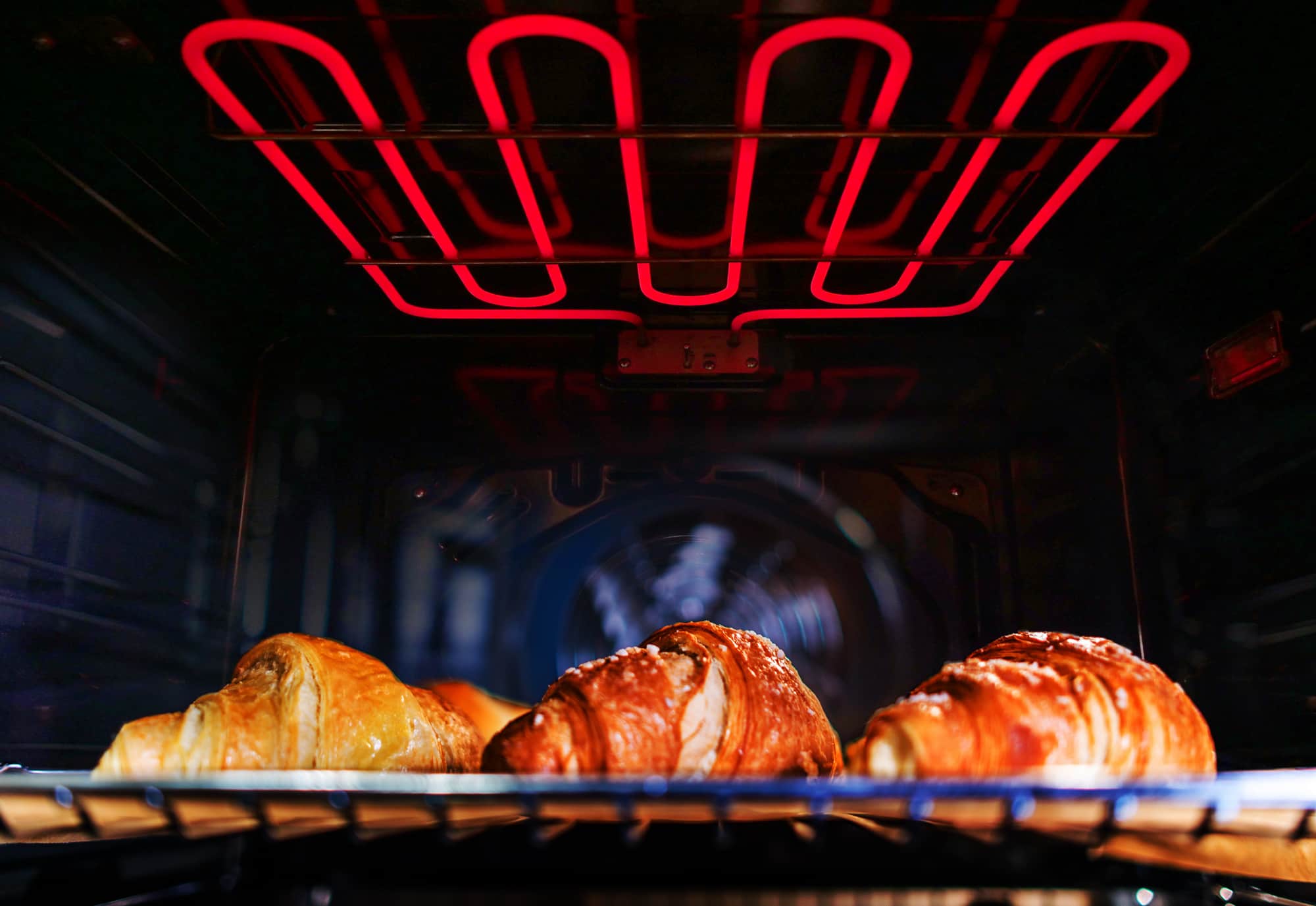 Double electric built-in wall oven with glowing heating elements and baking rack