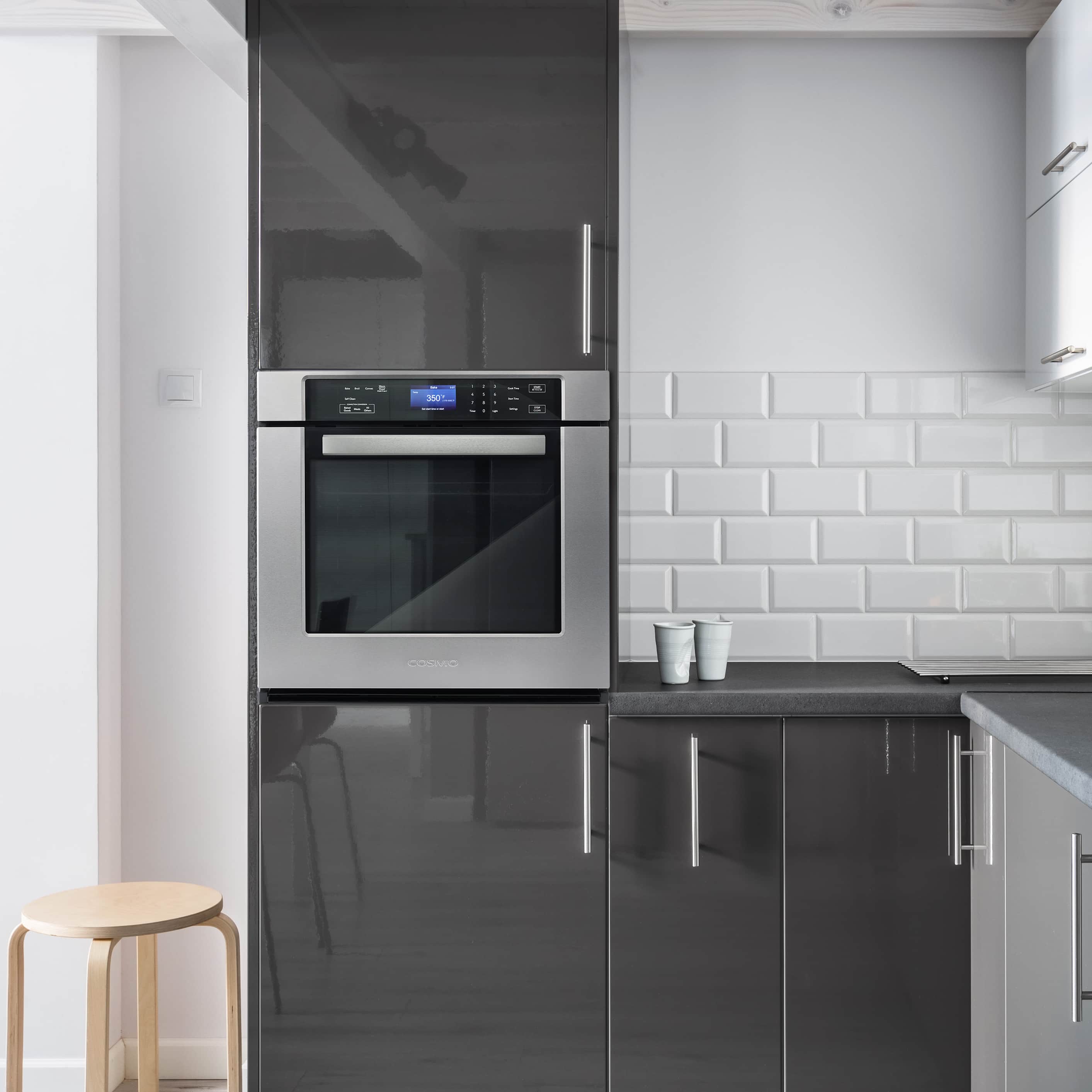 Built-in COSMO stainless steel electric wall oven with black glass door and handle