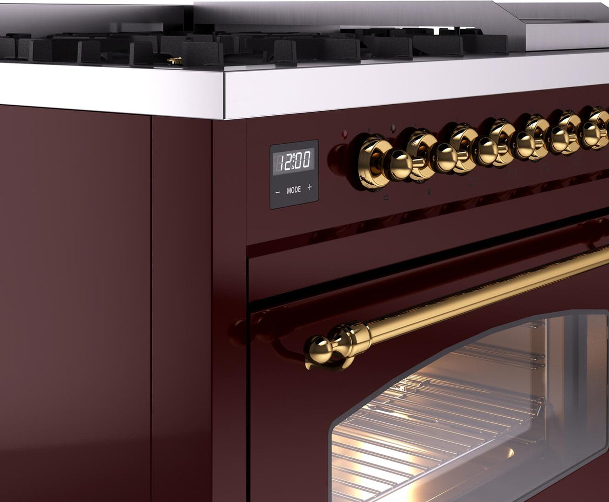 Burgundy dual fuel range close-up of brass control knobs, display, and oven window