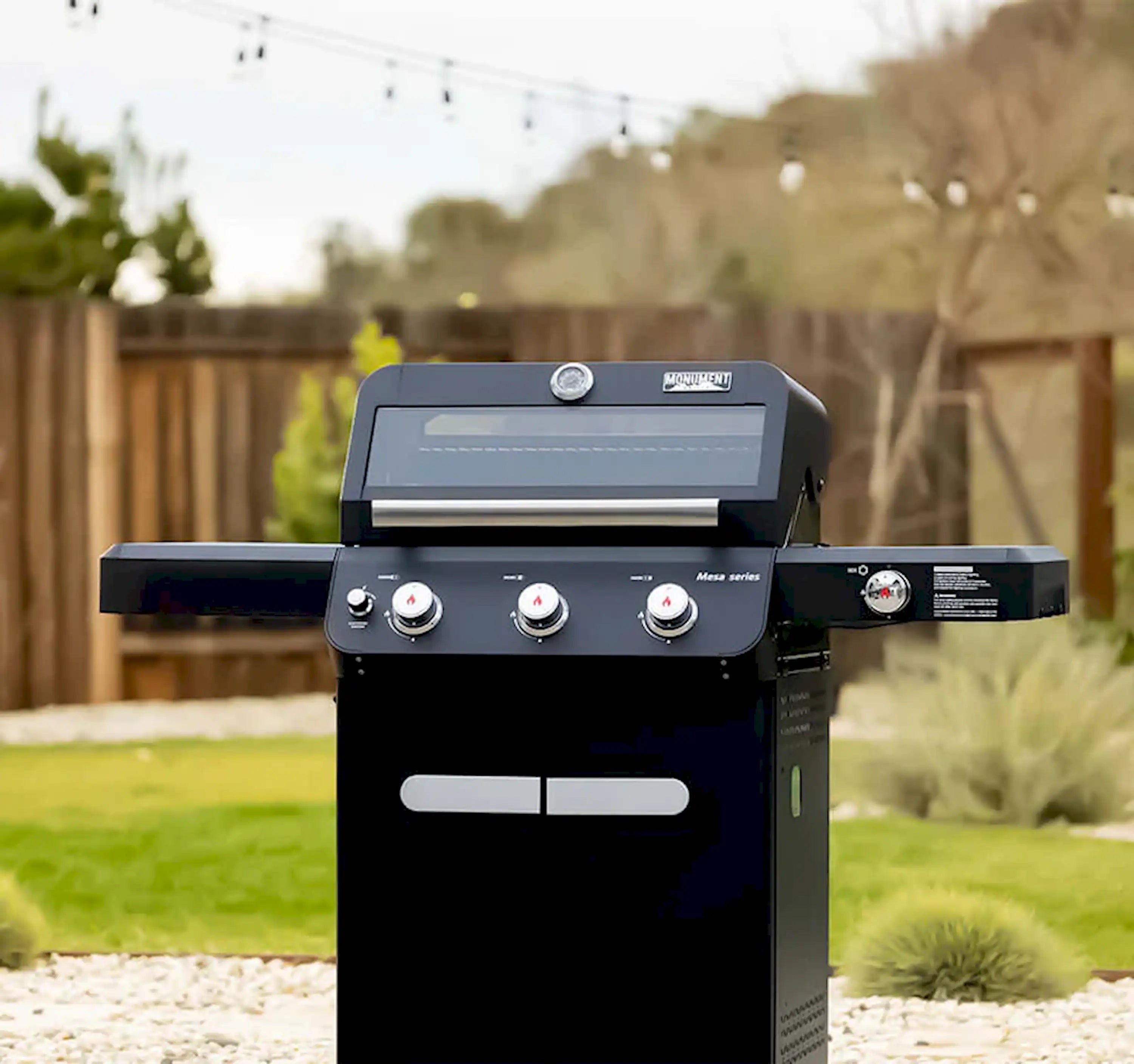 Black 3-burner propane gas grill with lid closed and two front doors