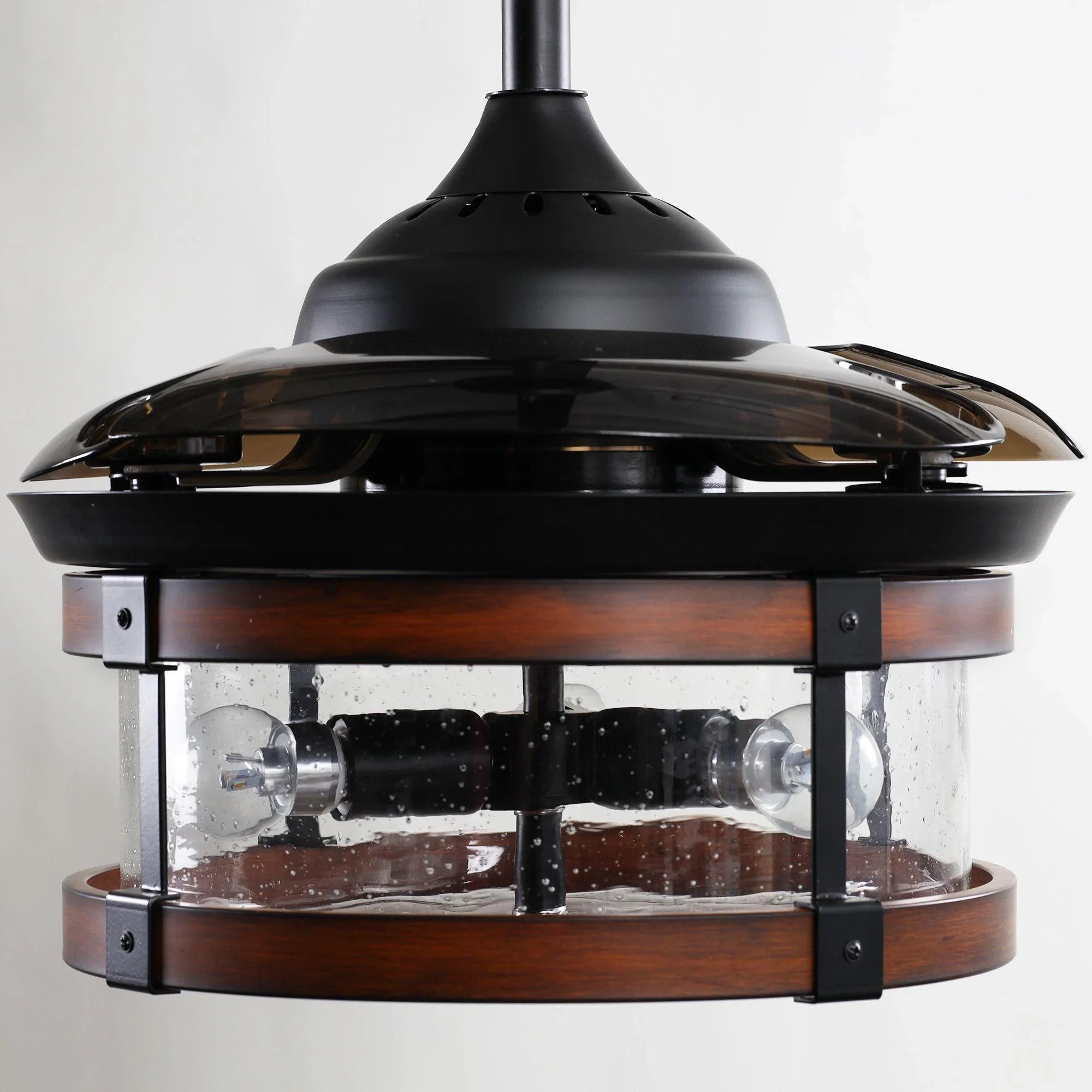 Close-up of black ceiling fan light with clear glass panels and wood band.